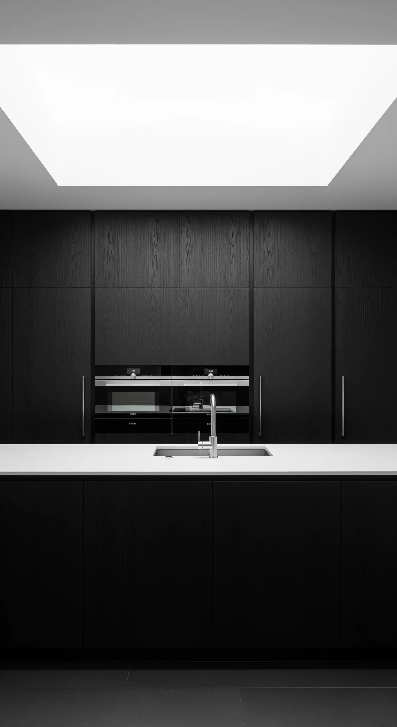 Cucina total black con design senza maniglie, top bianco e un grande lucernario.