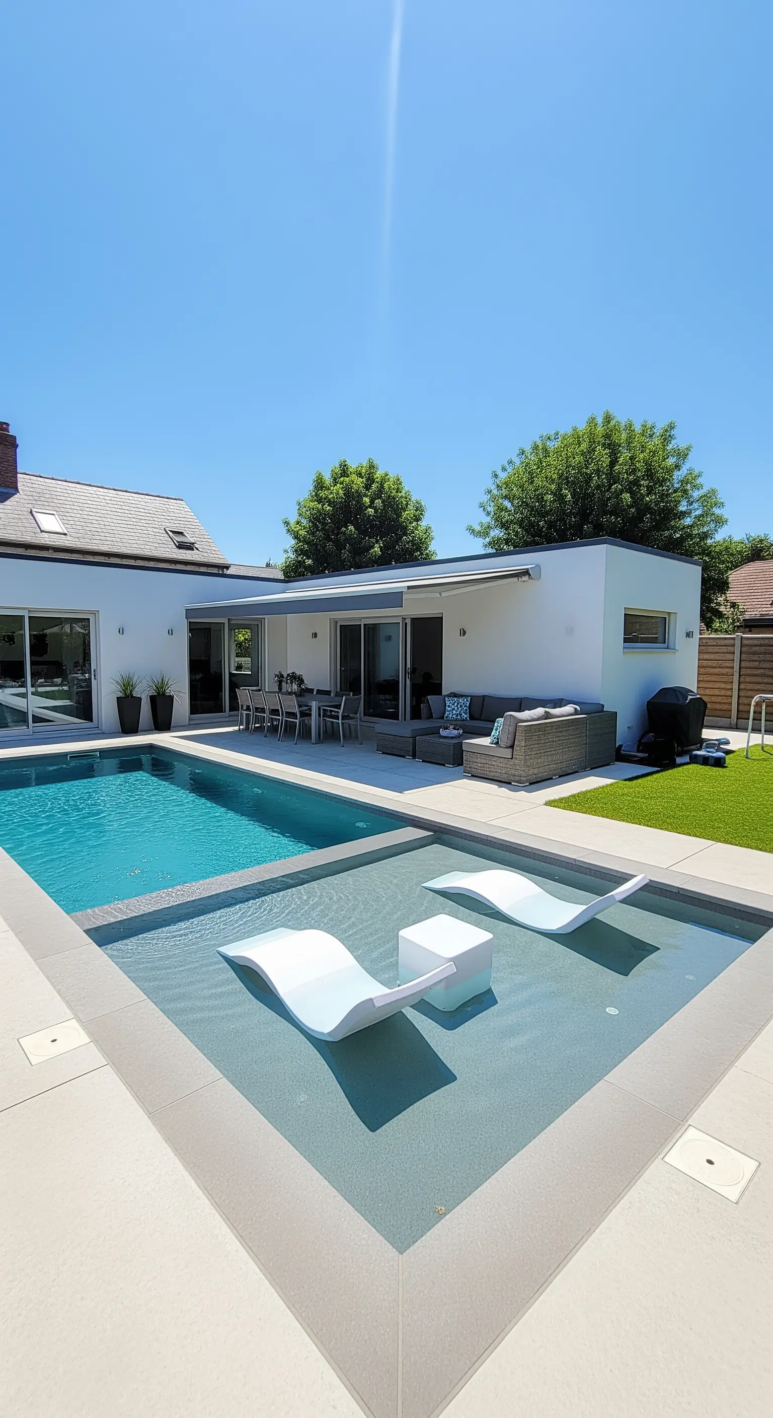 Chaise longue bianche di design in una zona di acqua bassa all'interno della piscina