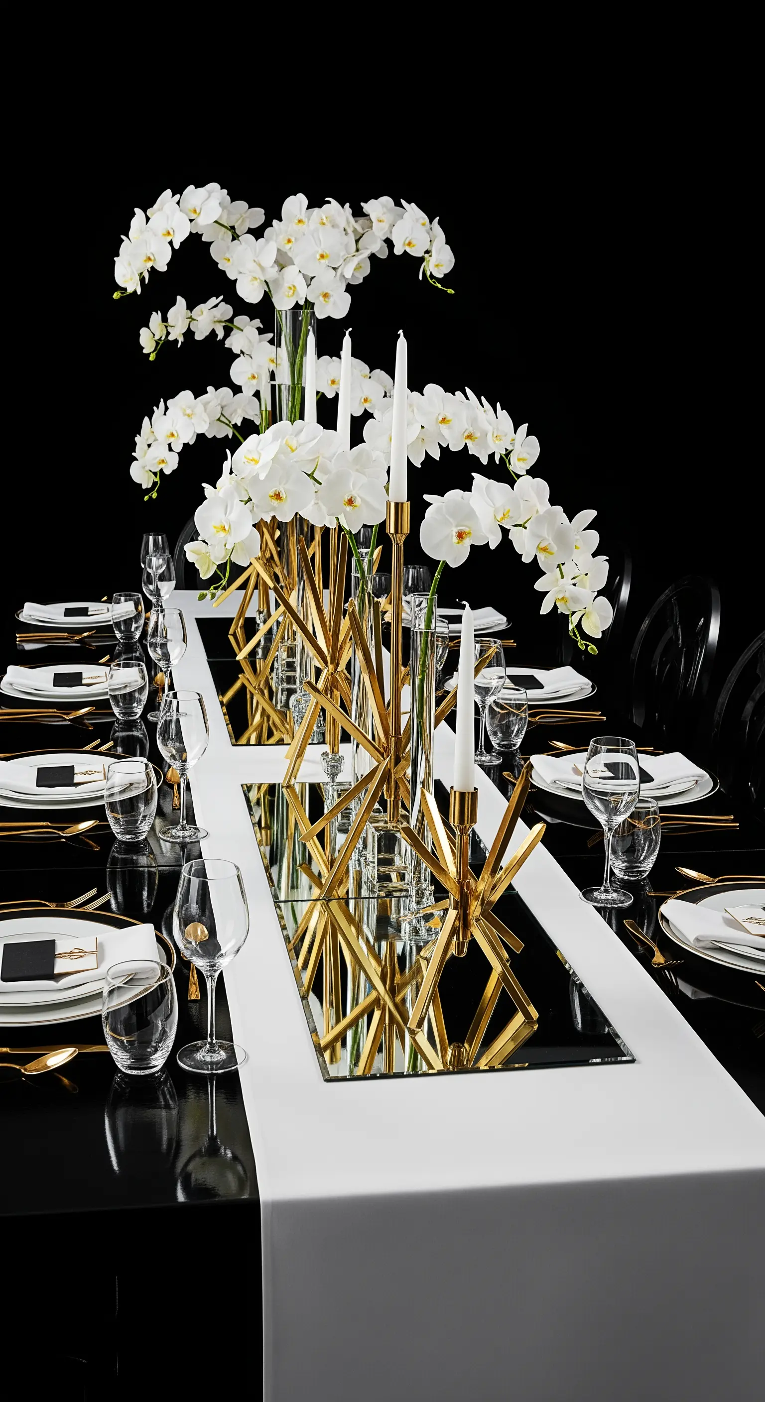 Tavola moderna con runner a specchio, candelabri geometrici e orchidee bianche.