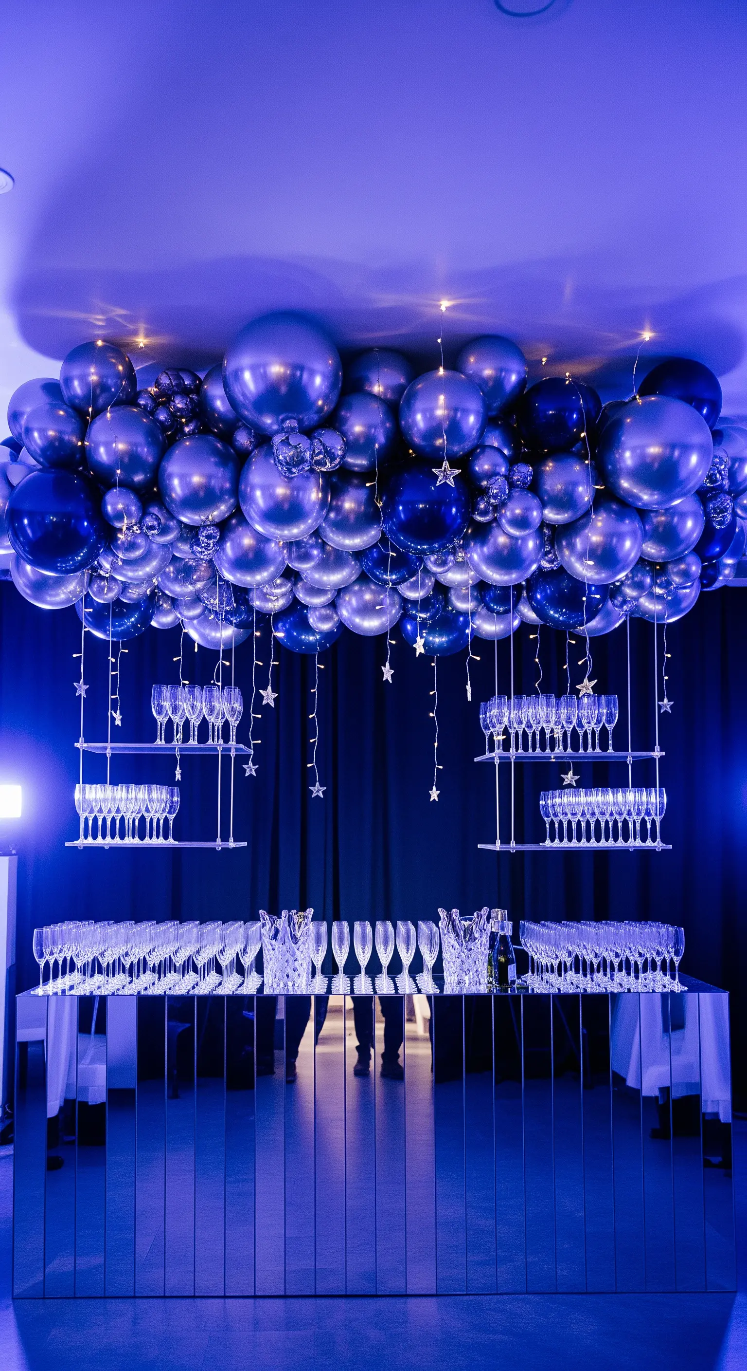 Bar specchiato con allestimento di palloncini blu metallizzato e argento sospesi.