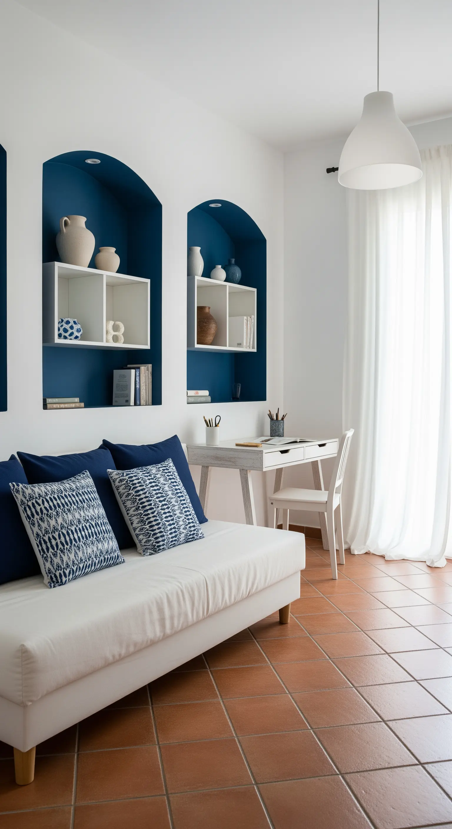 Salotto in stile mediterraneo con divano bianco, nicchie blu e pavimento in cotto.