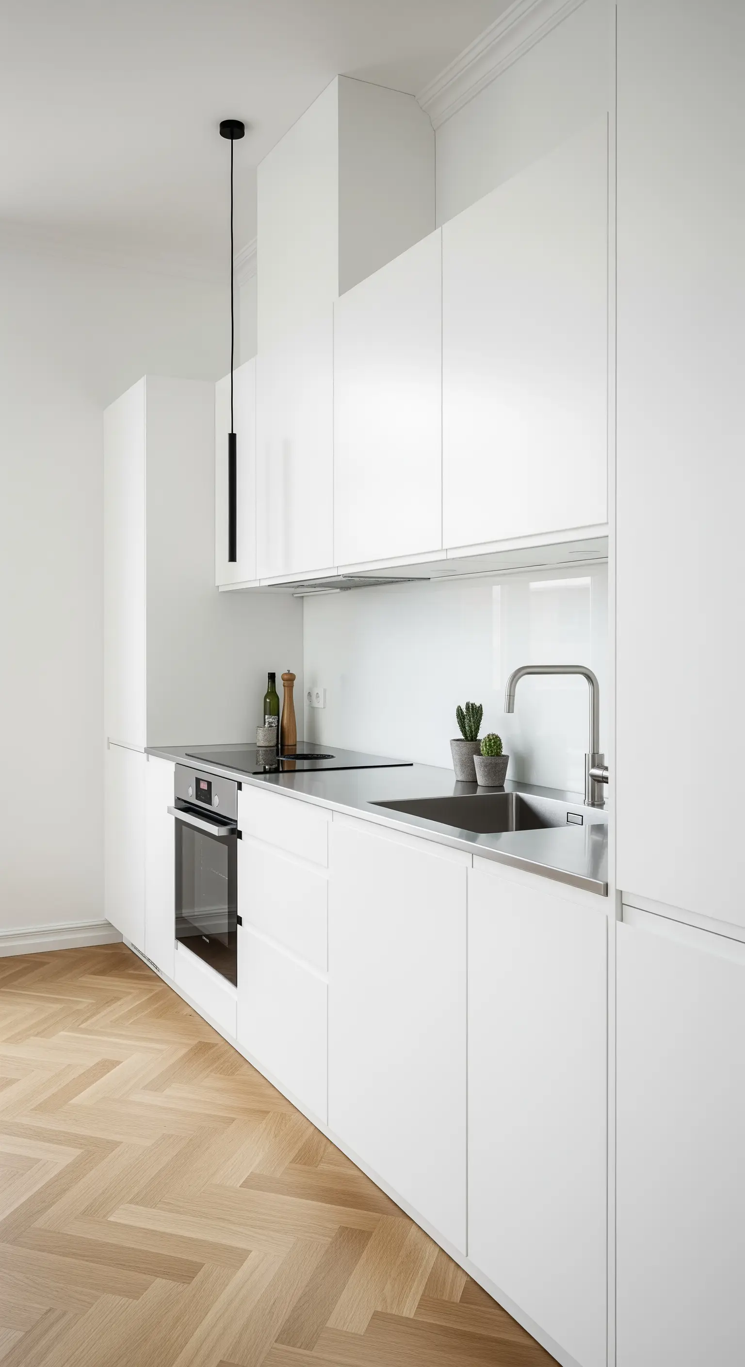 Cucina minimalista bianca e acciaio, riscaldata da un parquet a spina di pesce.