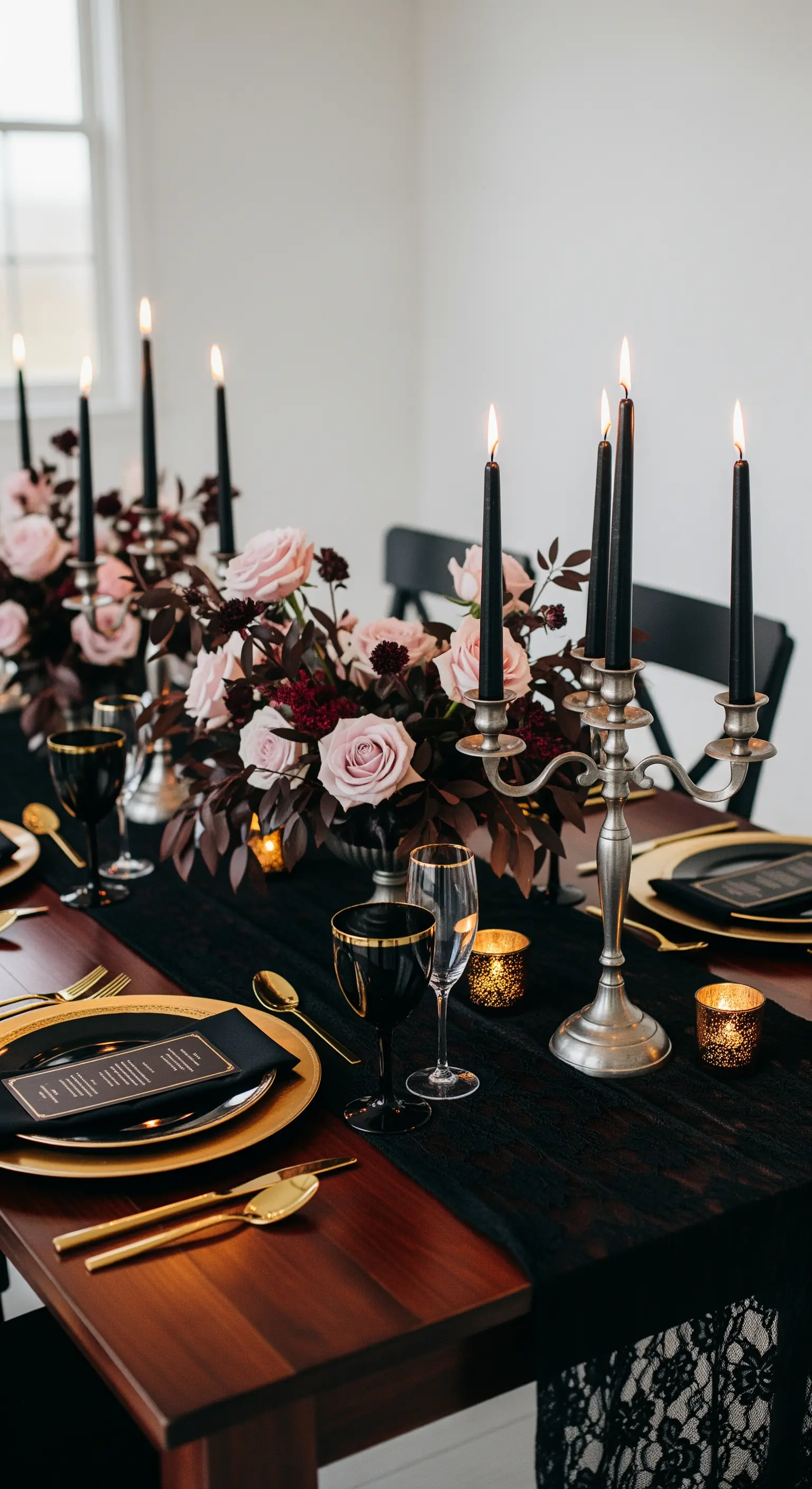 Tavola nuziale drammatica con pizzo nero, candele nere, dettagli dorati e fiori rosa.