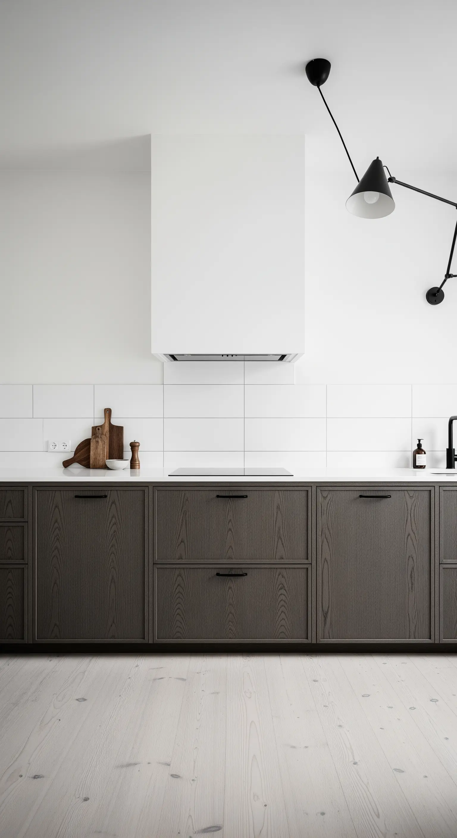 Cucina scandinava con mobili in legno scuro, piastrelle bianche e pavimento chiaro.
