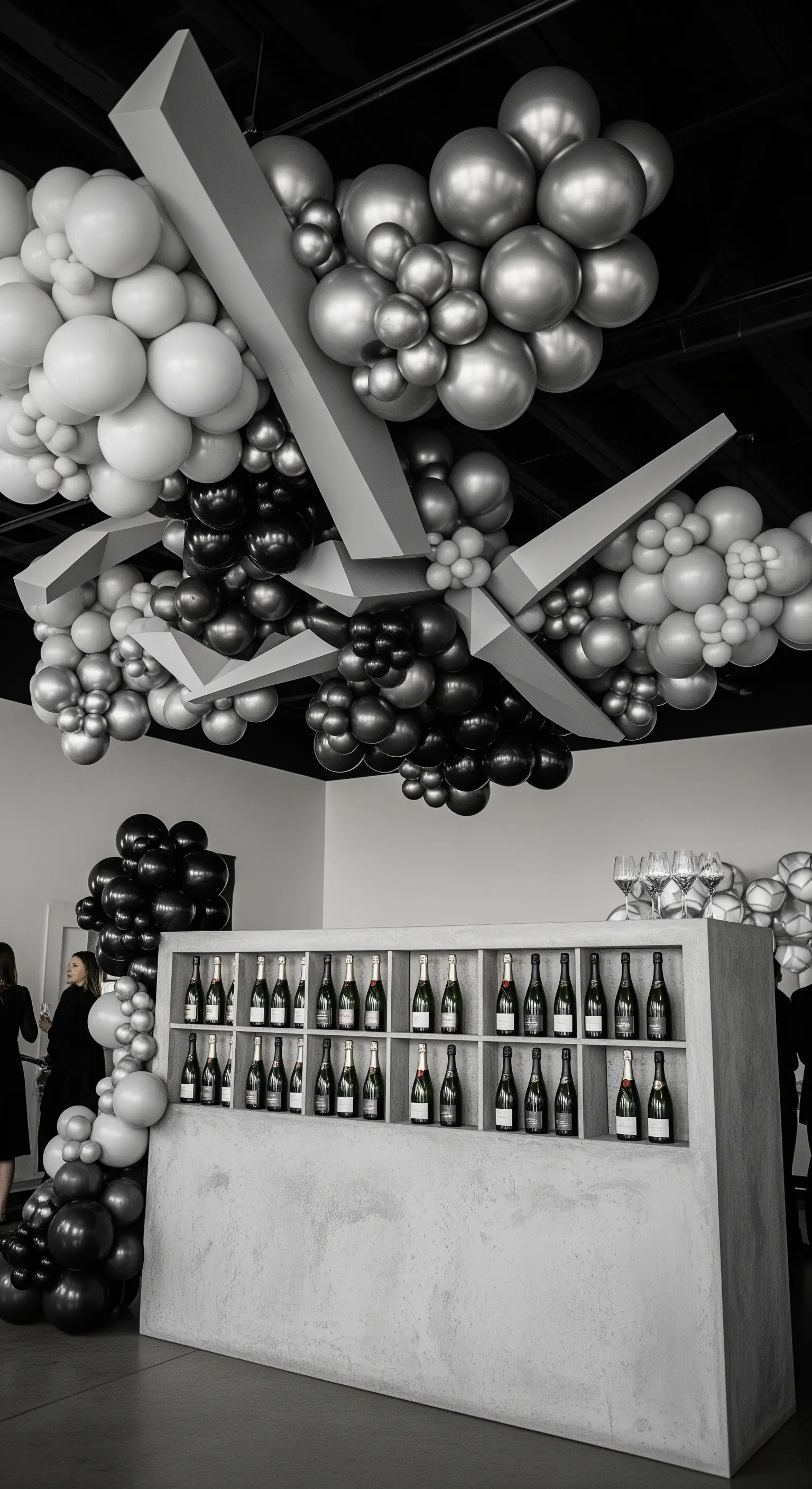 Installazione a soffitto con palloncini bianchi, neri e argento in uno spazio moderno.