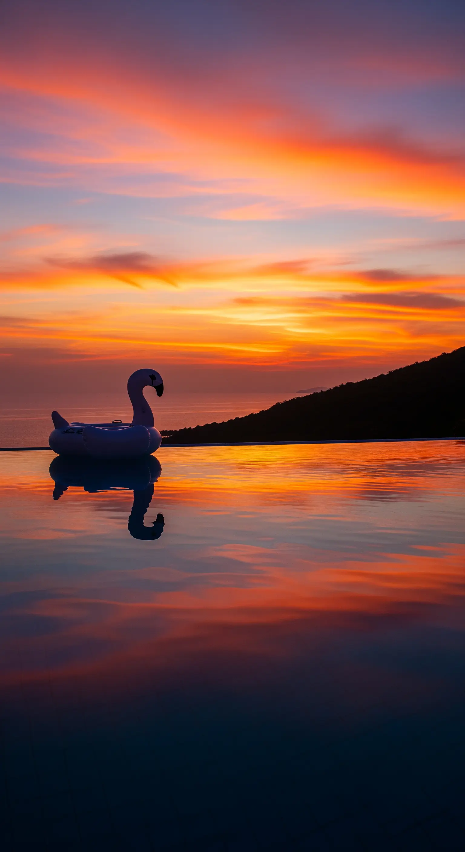 Gonfiabile a forma di fenicottero in una piscina a sfioro durante un tramonto spettacolare.