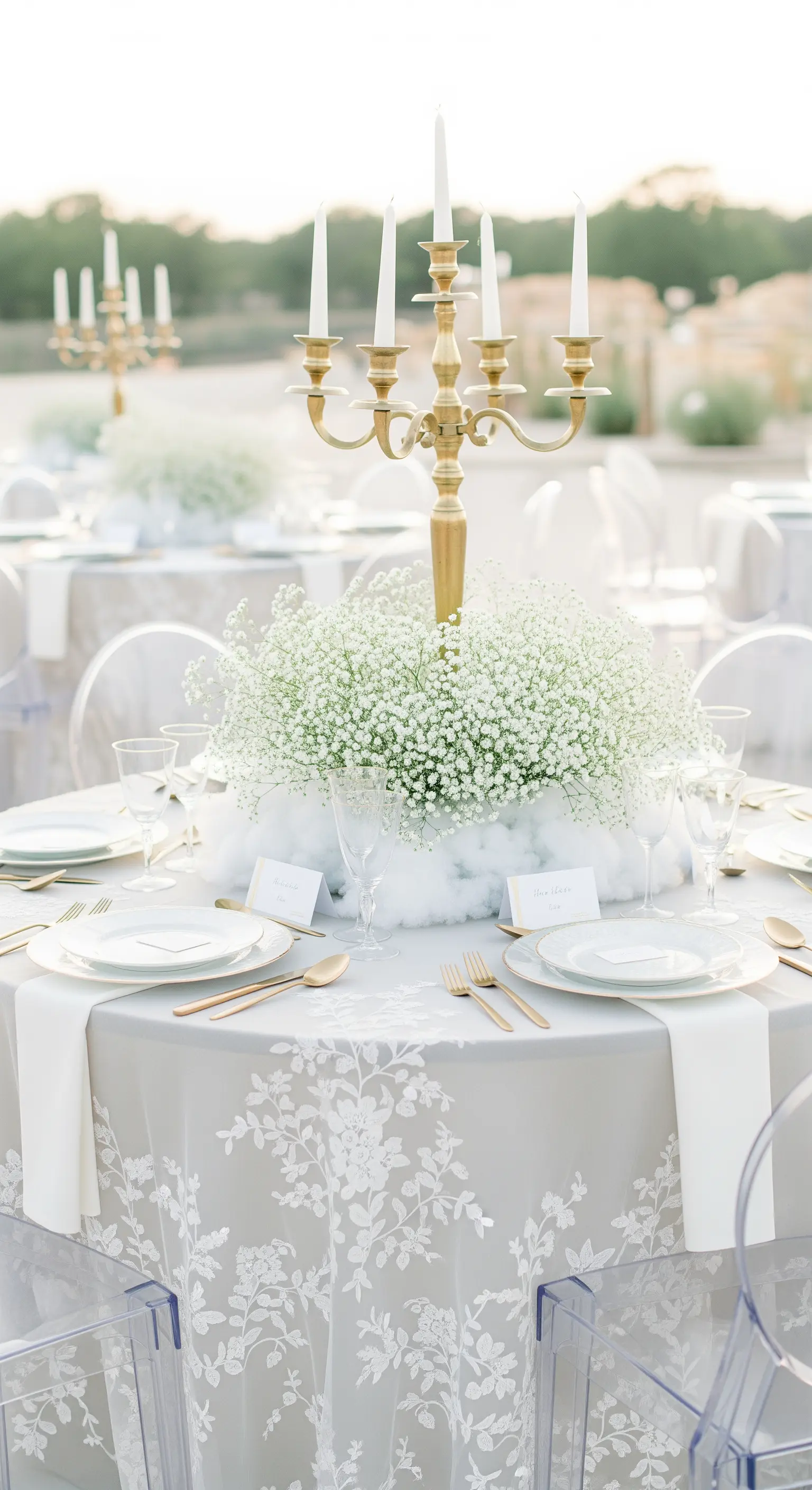 Tavola rotonda con centrotavola a nuvola di gypsophila e candelabro dorato.
