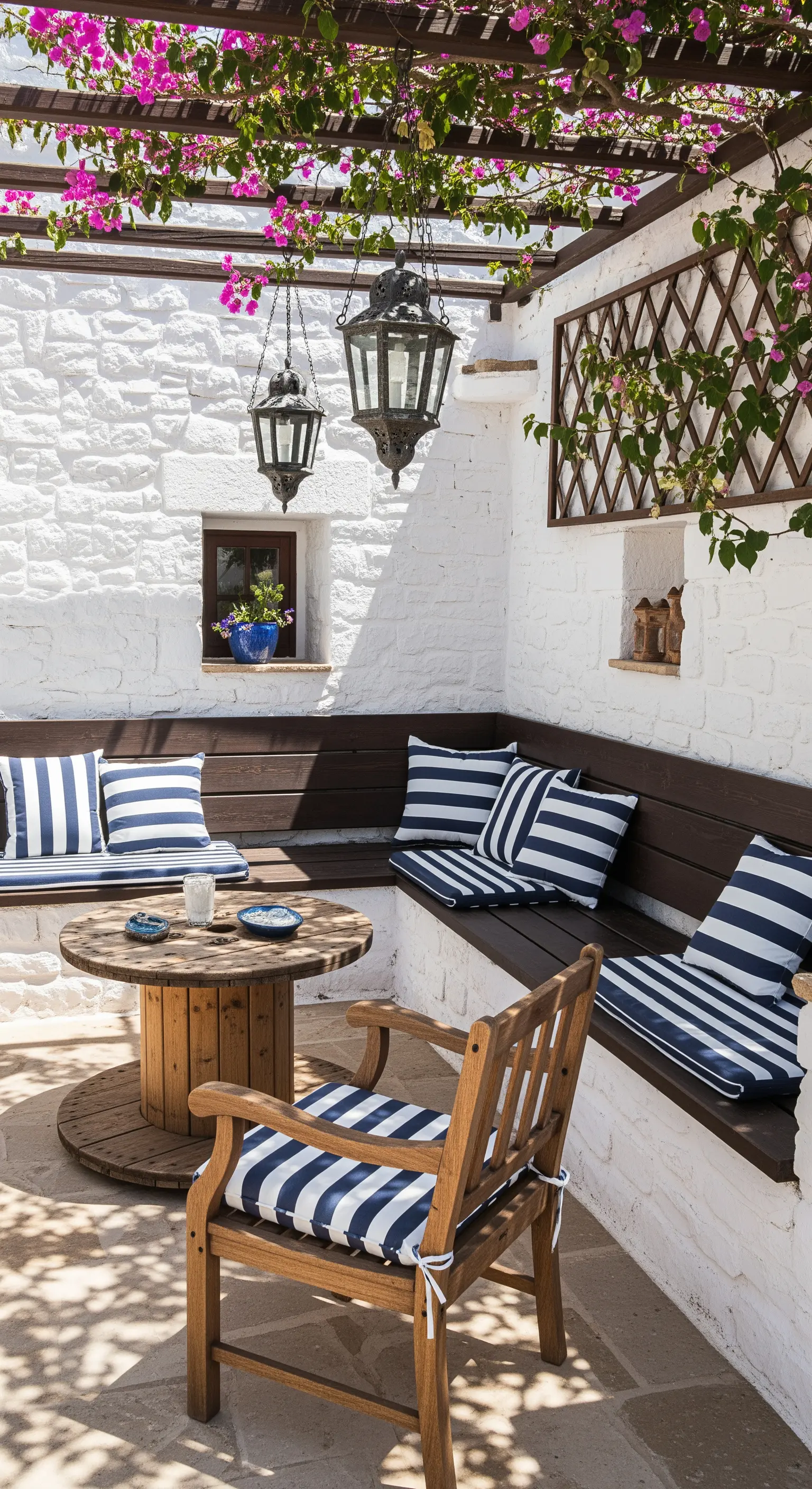 Patio con panca ad angolo, cuscini a righe blu e bianche e una pergola di bouganville.