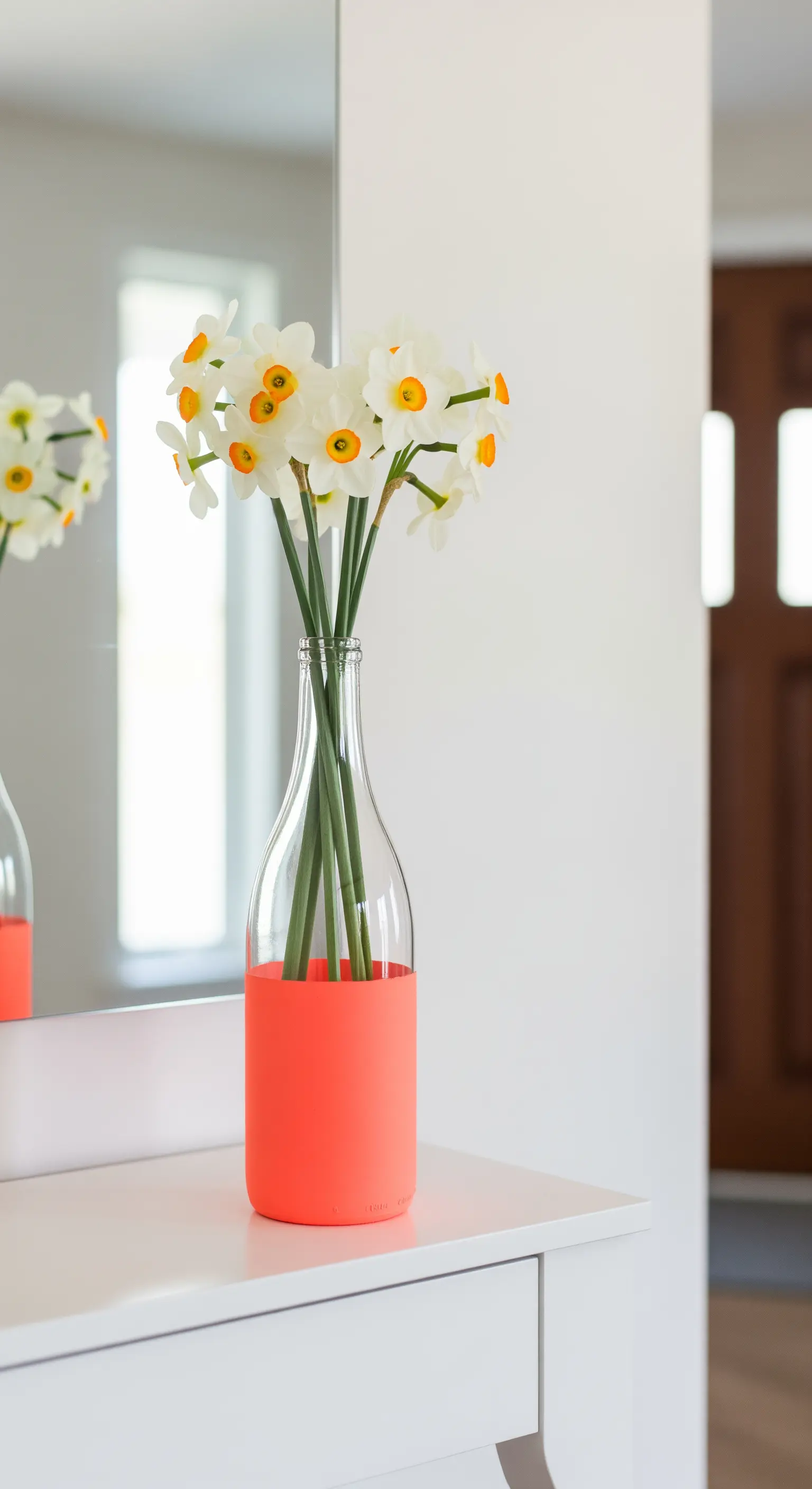 Bottiglia di vino in vetro trasparente con la base immersa in vernice color corallo.