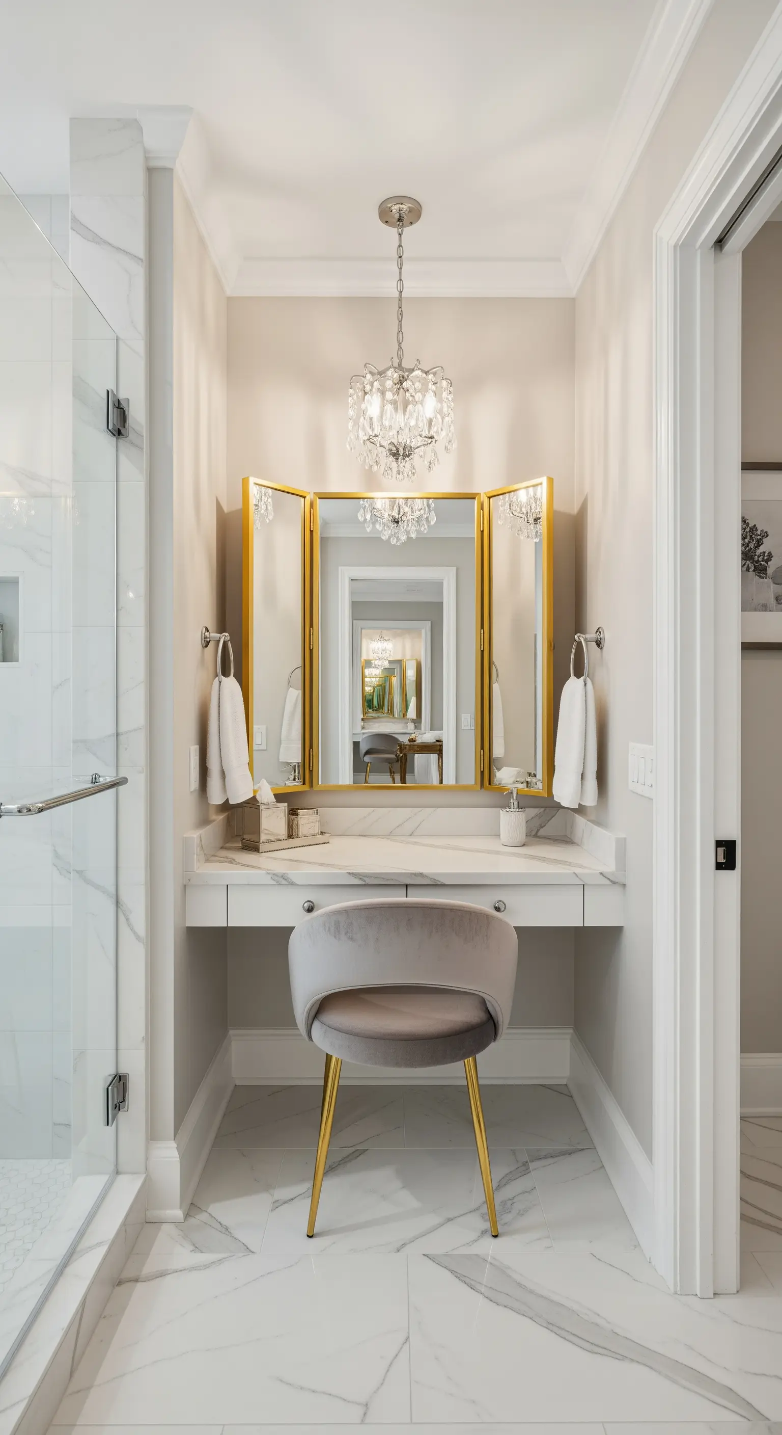 Angolo trucco in bagno con specchio a tre ante dorato, sedia in velluto e piccolo lampadario.