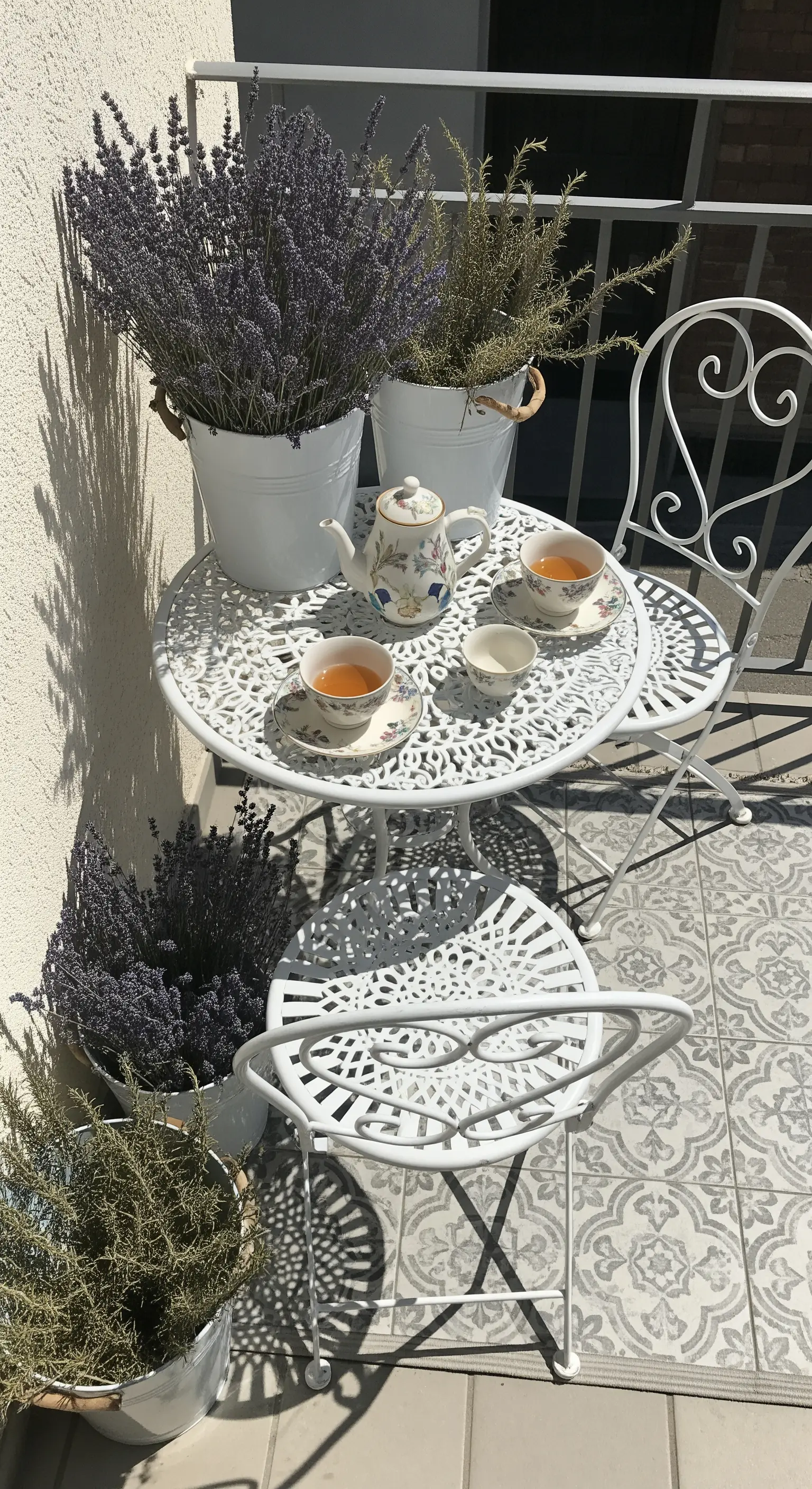 Tavolino da caffè bianco circondato da vasi di latta bianca pieni di lavanda e rosmarino.