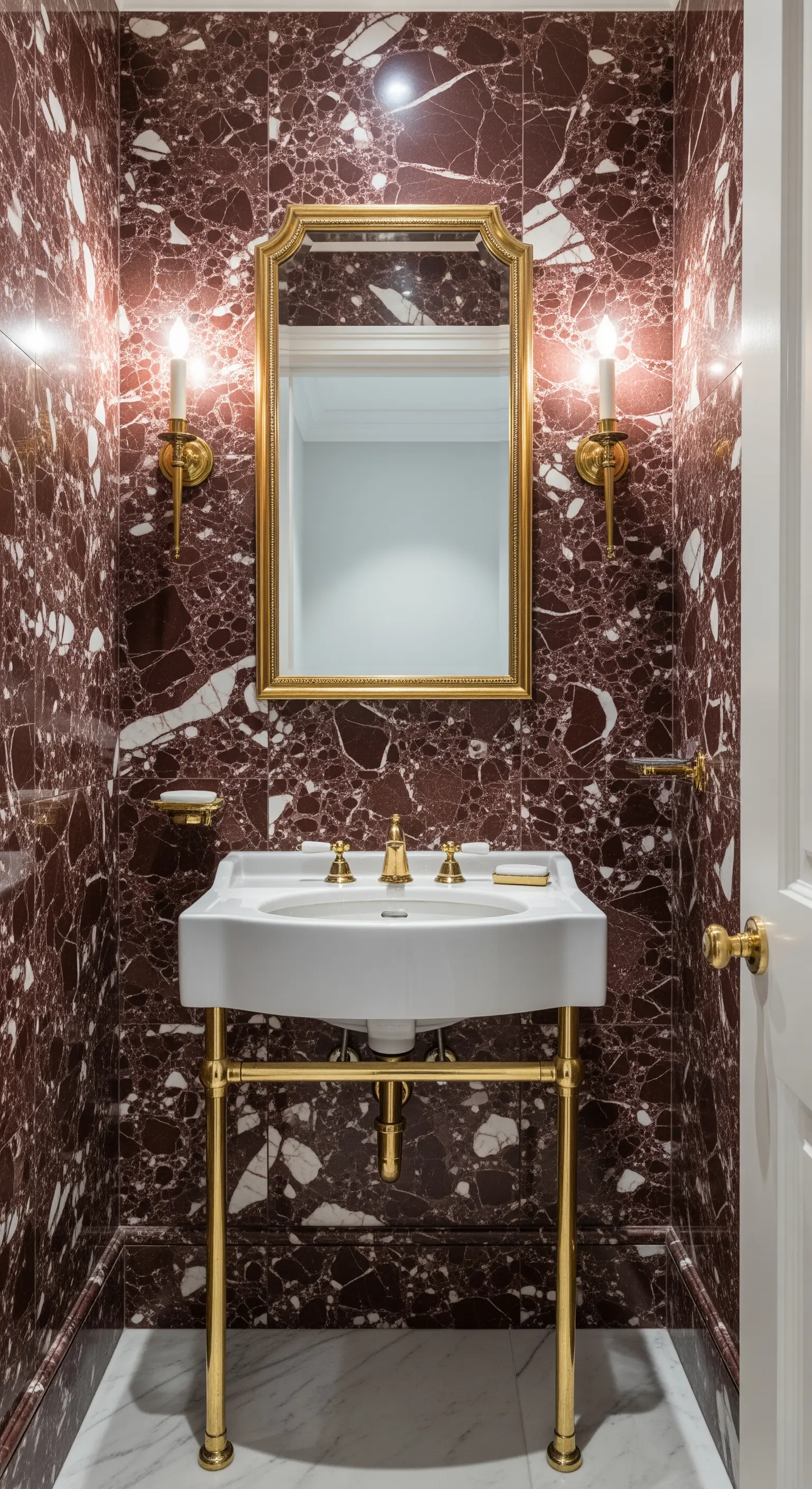 Bagno piccolo rivestito in marmo rosso porpora con lavabo e specchio con dettagli in ottone.
