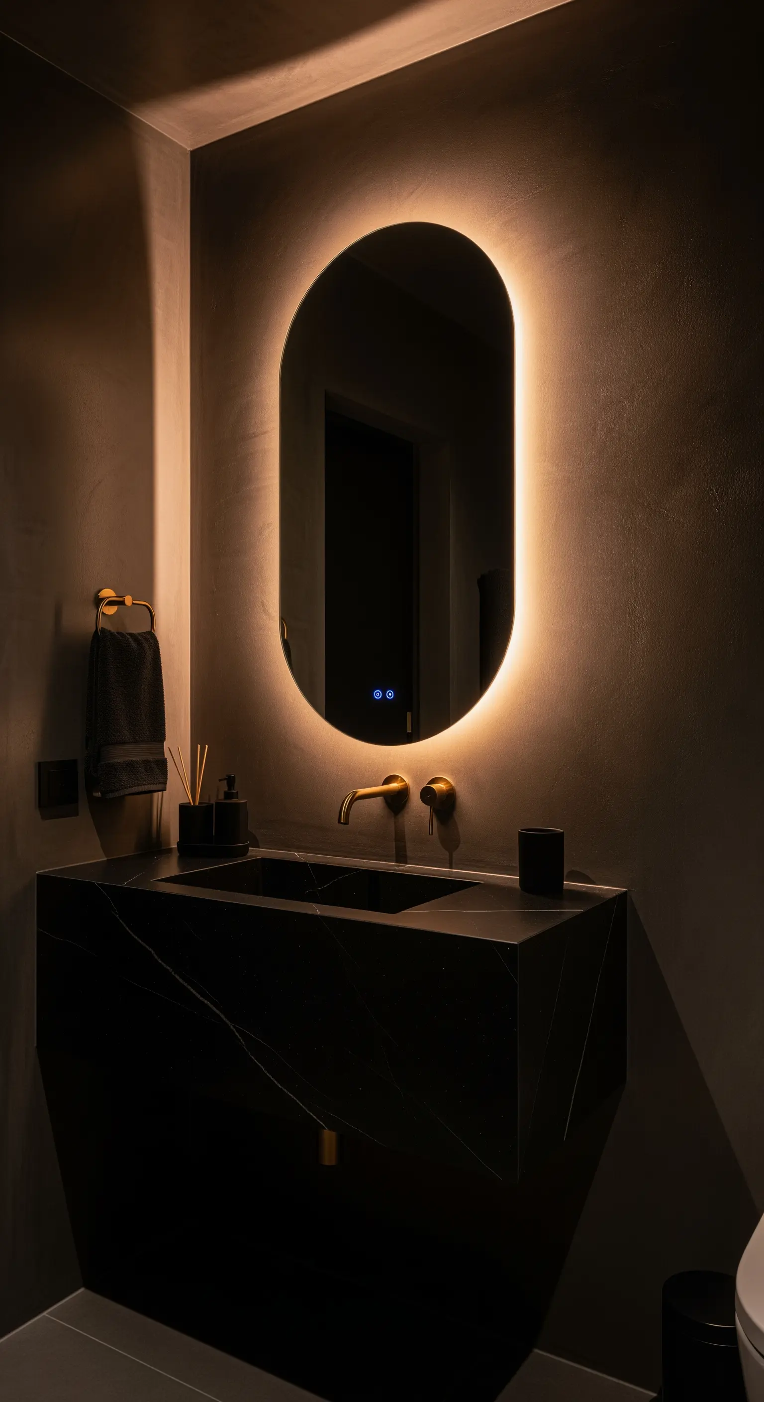 Specchio ovale retroilluminato in un bagno scuro con lavabo in marmo nero.