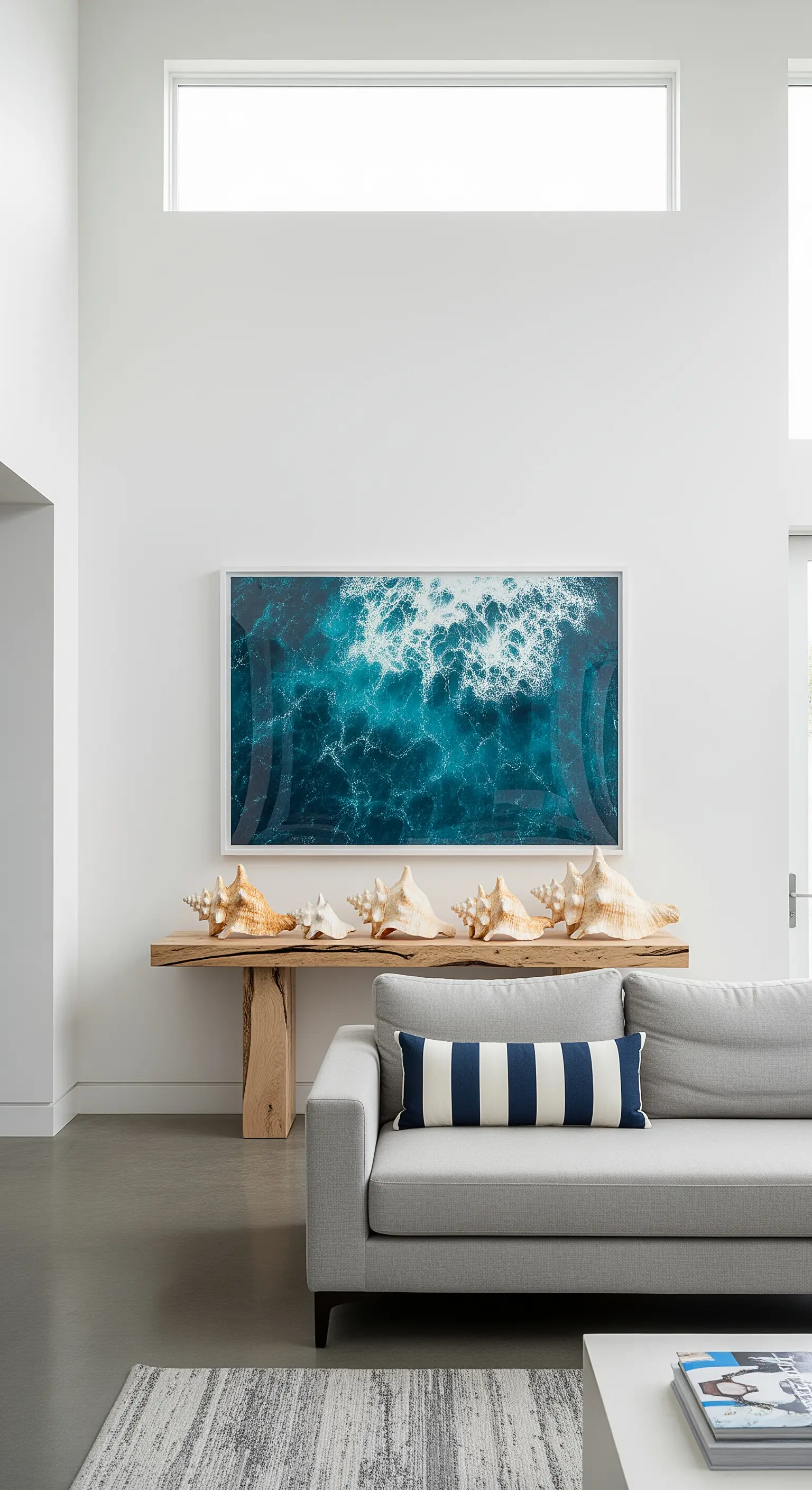 Parete bianca con grande quadro di onde oceaniche e consolle con conchiglie decorative.