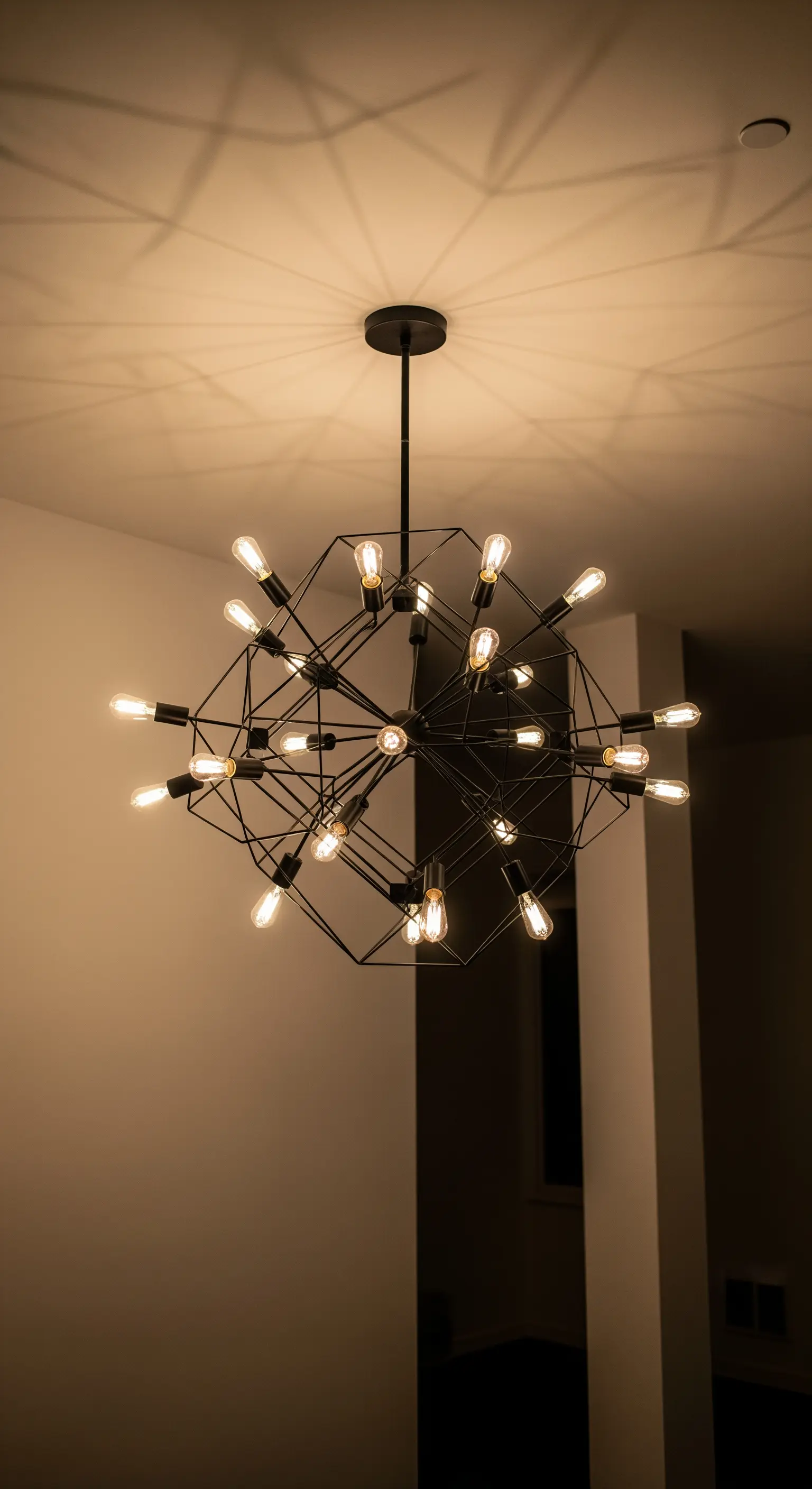 Lampadario moderno a struttura geometrica nera con molte lampadine a vista.