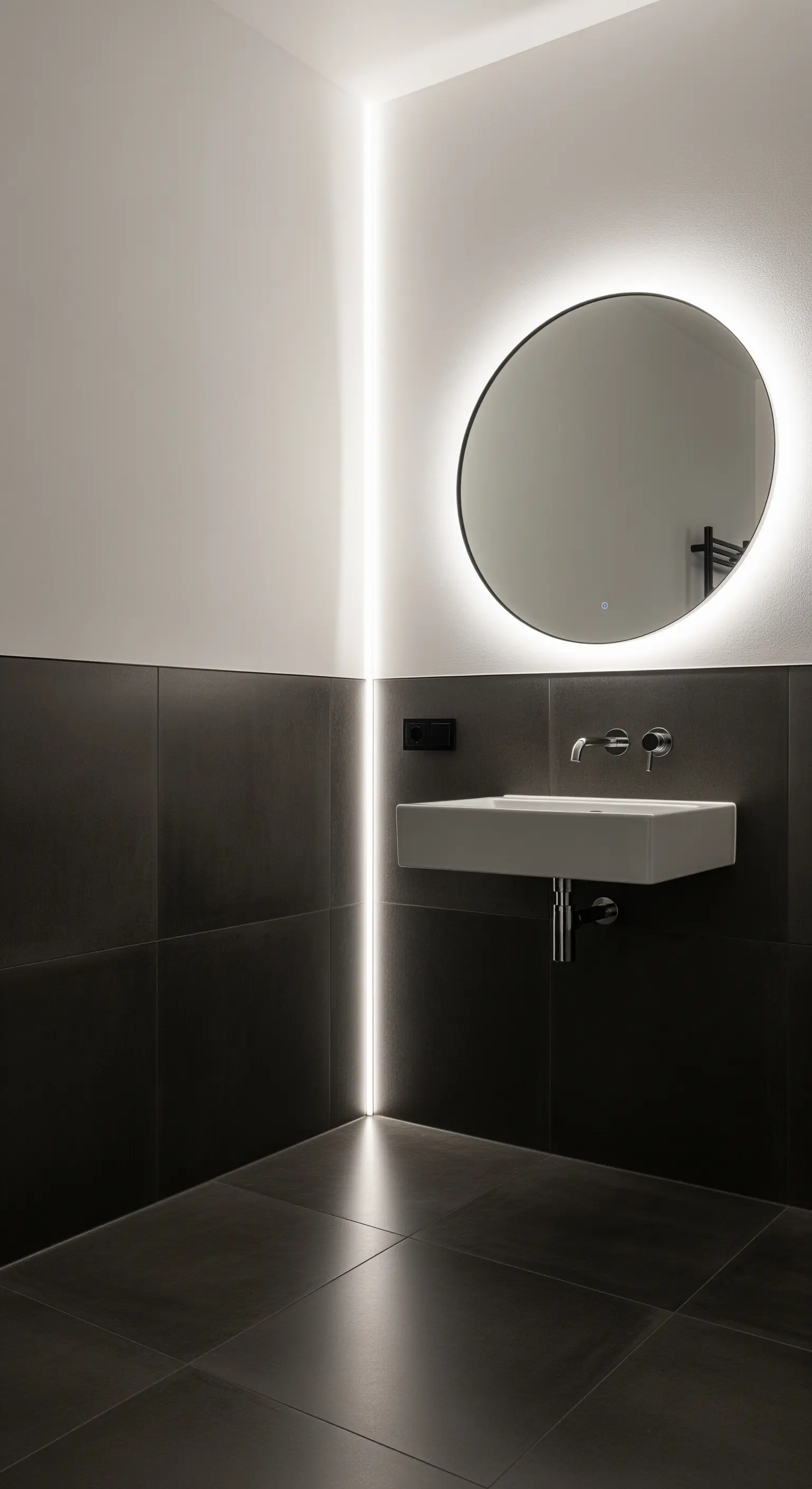 Bagno minimalista con una striscia LED verticale nell'angolo e specchio rotondo retroilluminato.