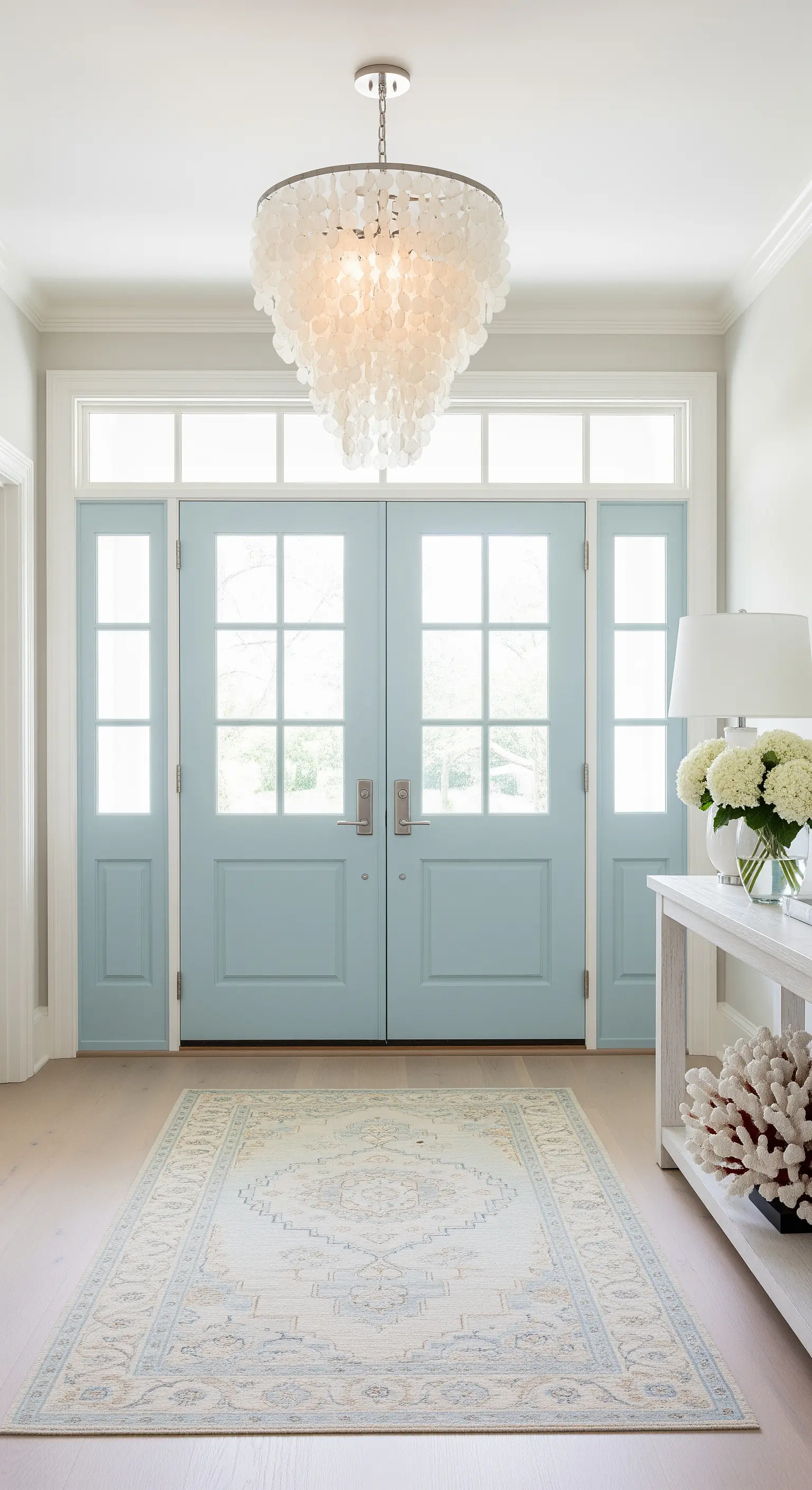 Ingresso in stile costiero con porte azzurre e lampadario di conchiglie capiz.