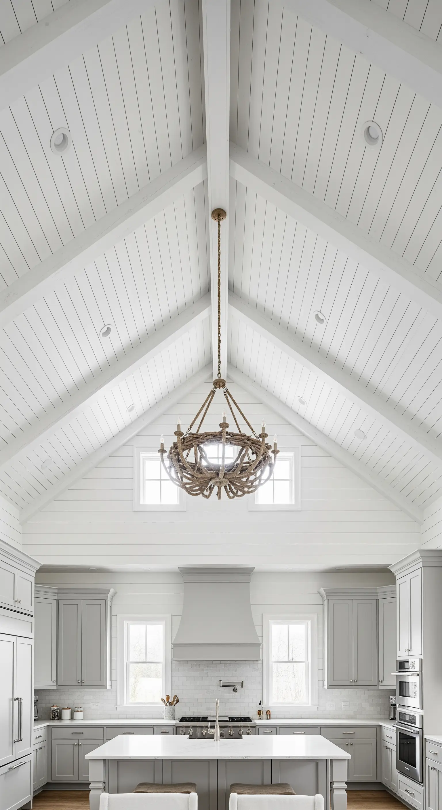 Grande cucina con soffitto a cattedrale in legno bianco e un lampadario in corda intrecciata.