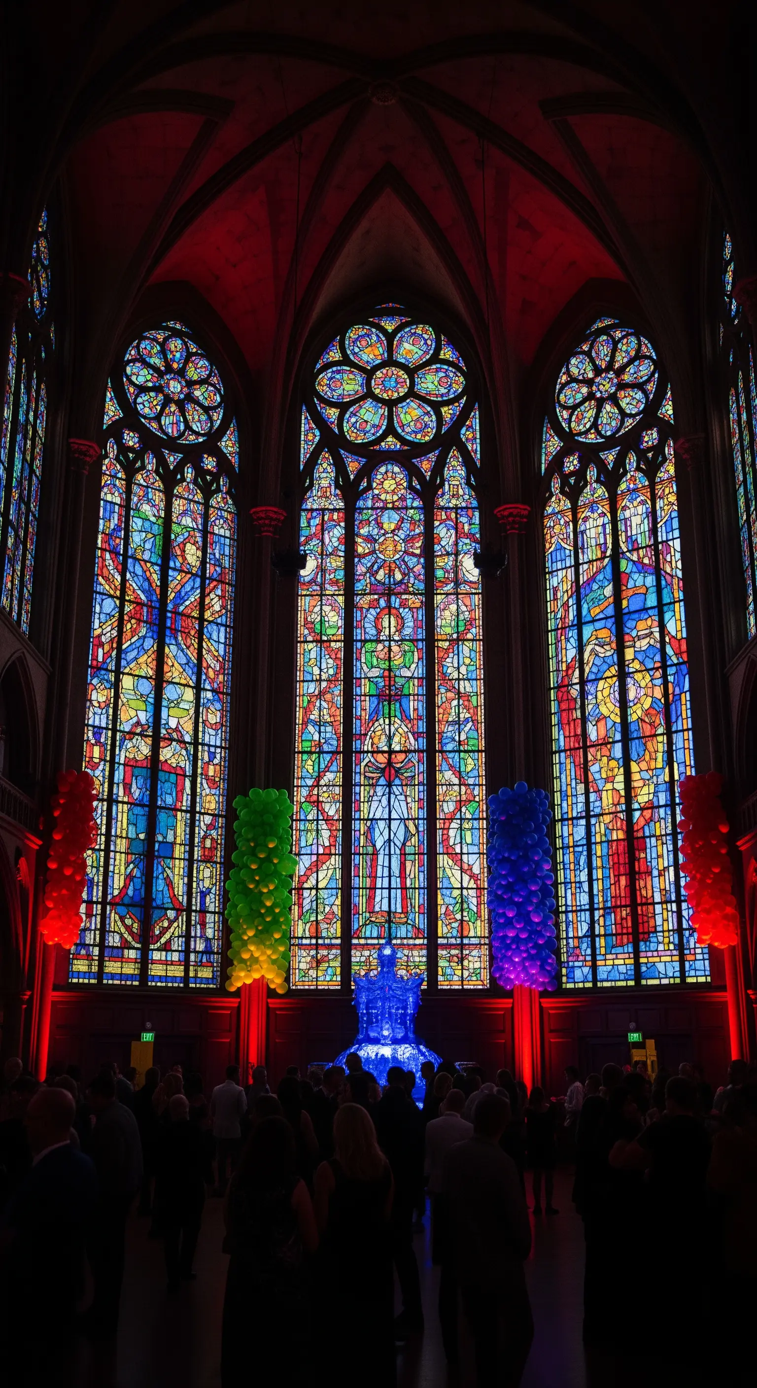 Interno di una cattedrale con vetrate colorate e colonne di palloncini illuminate.
