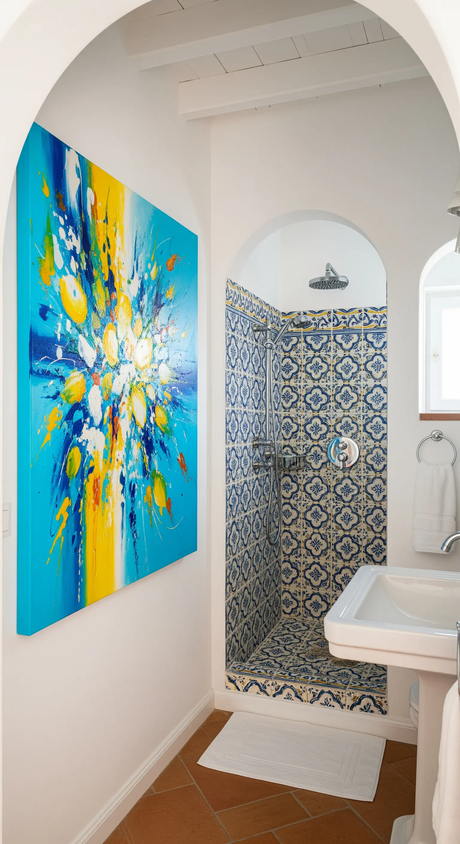 Bagno in stile mediterraneo con maioliche blu e un quadro astratto moderno molto colorato.