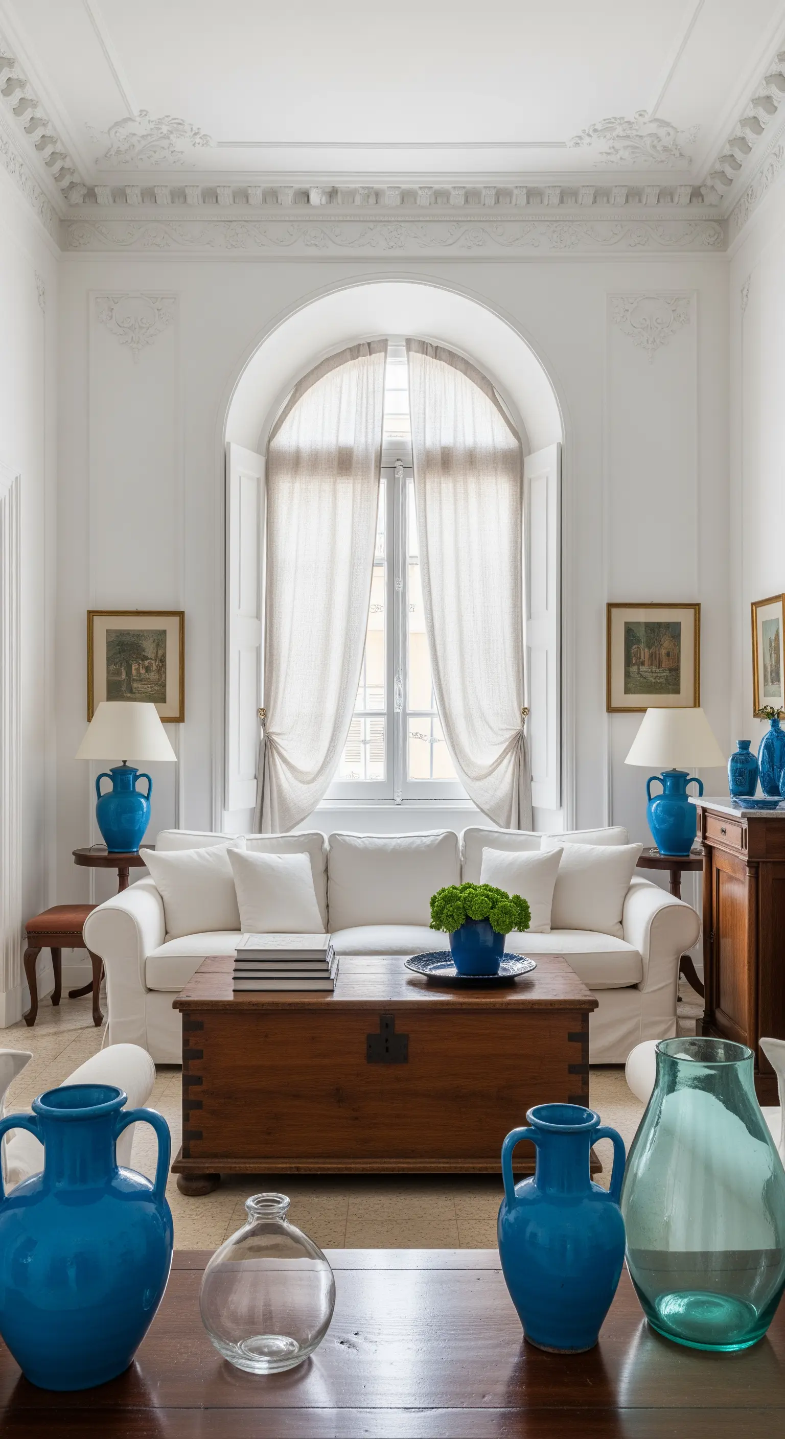 Soggiorno classico con divano bianco, due lampade blu simmetriche e un baule come tavolino.