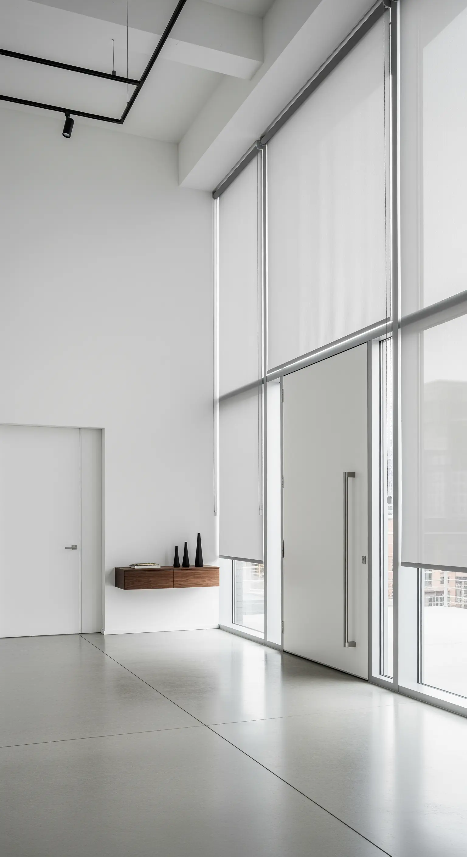 Ingresso minimalista a doppia altezza con tende a rullo bianche e una consolle sospesa in legno.