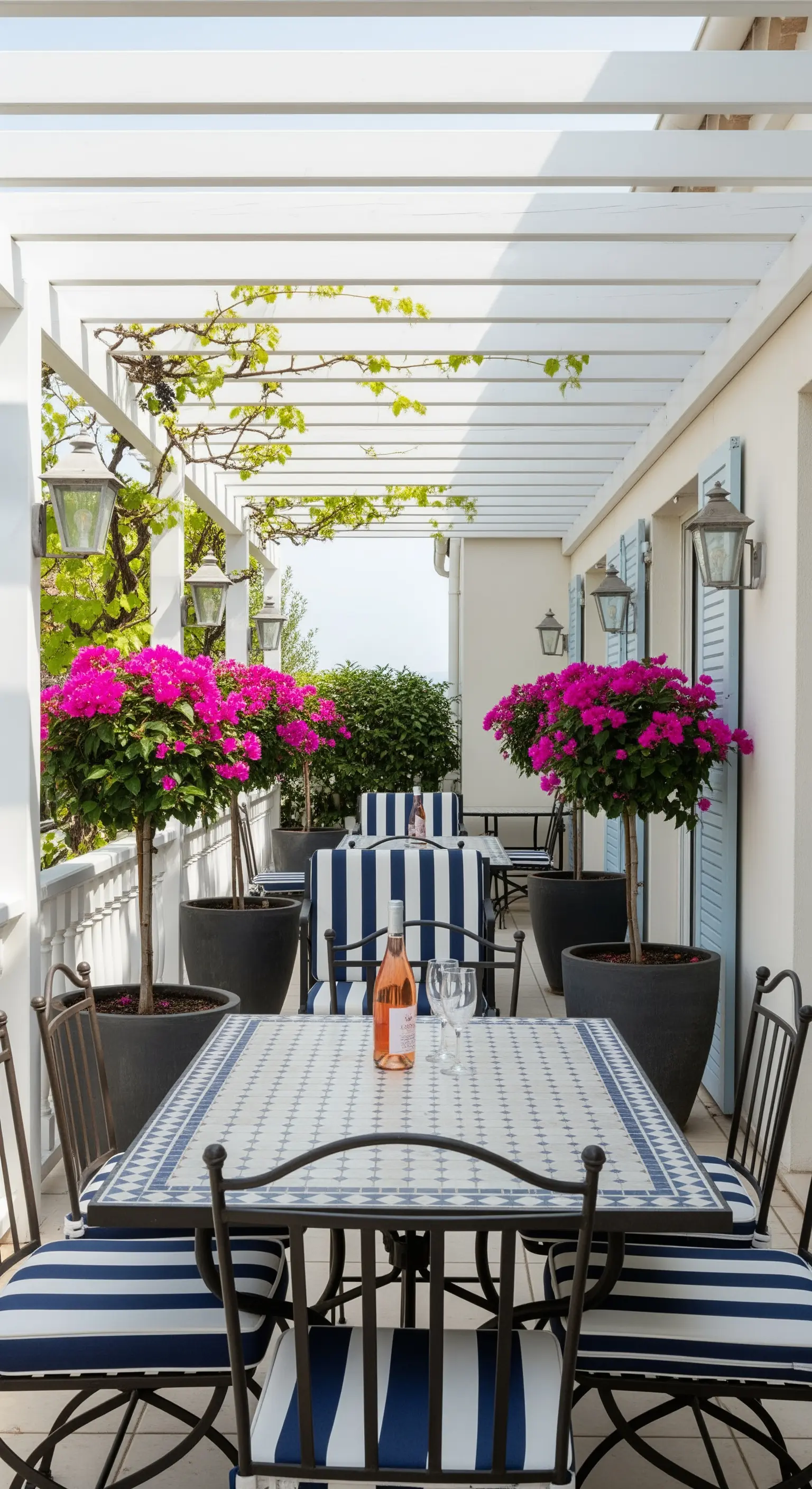 Terrazza in stile costiero con pergola bianca, cuscini a righe blu e tavolo in mosaico