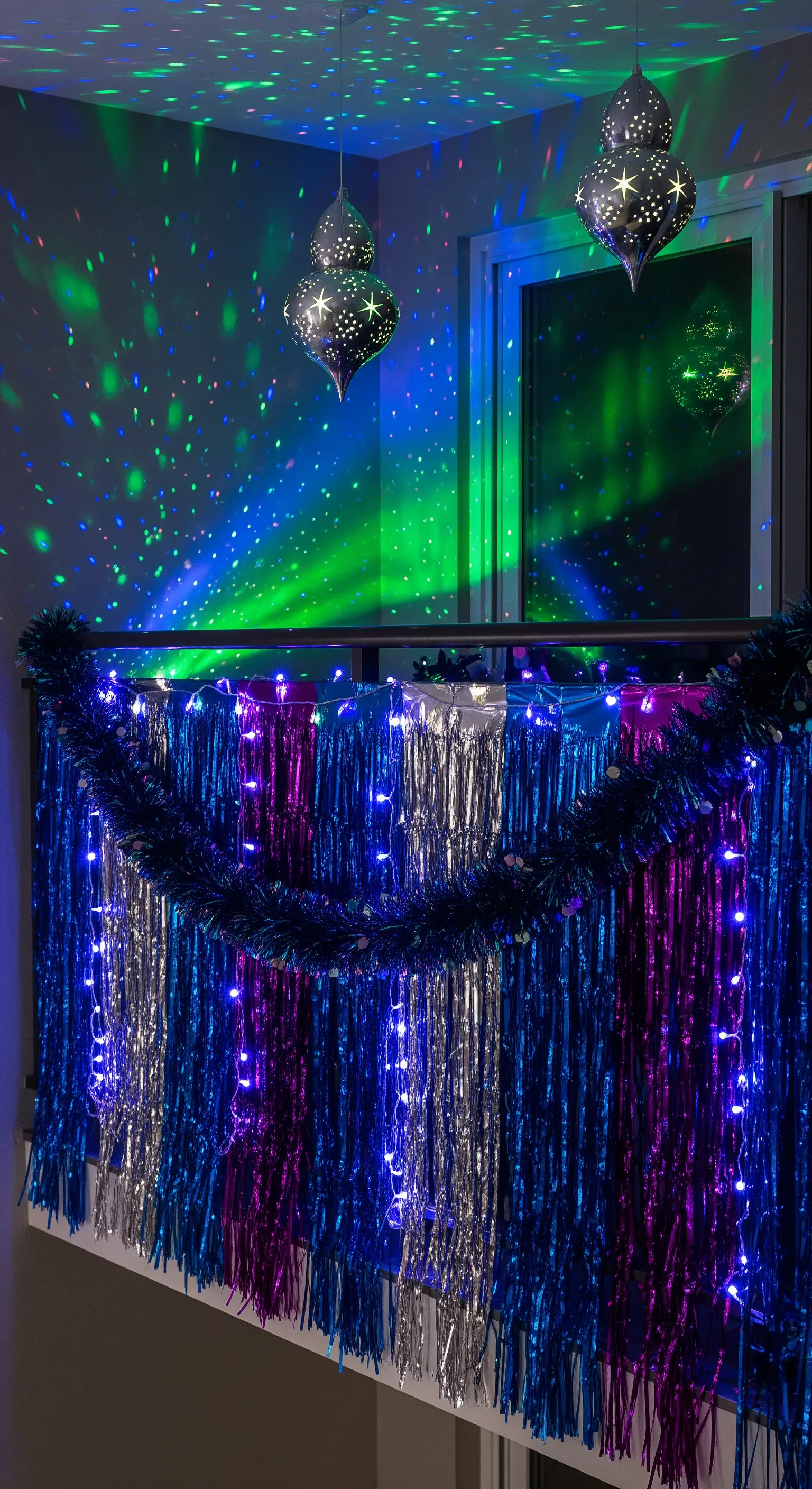 Balcone con festoni metallici blu e argento e luci da discoteca che proiettano punti colorati