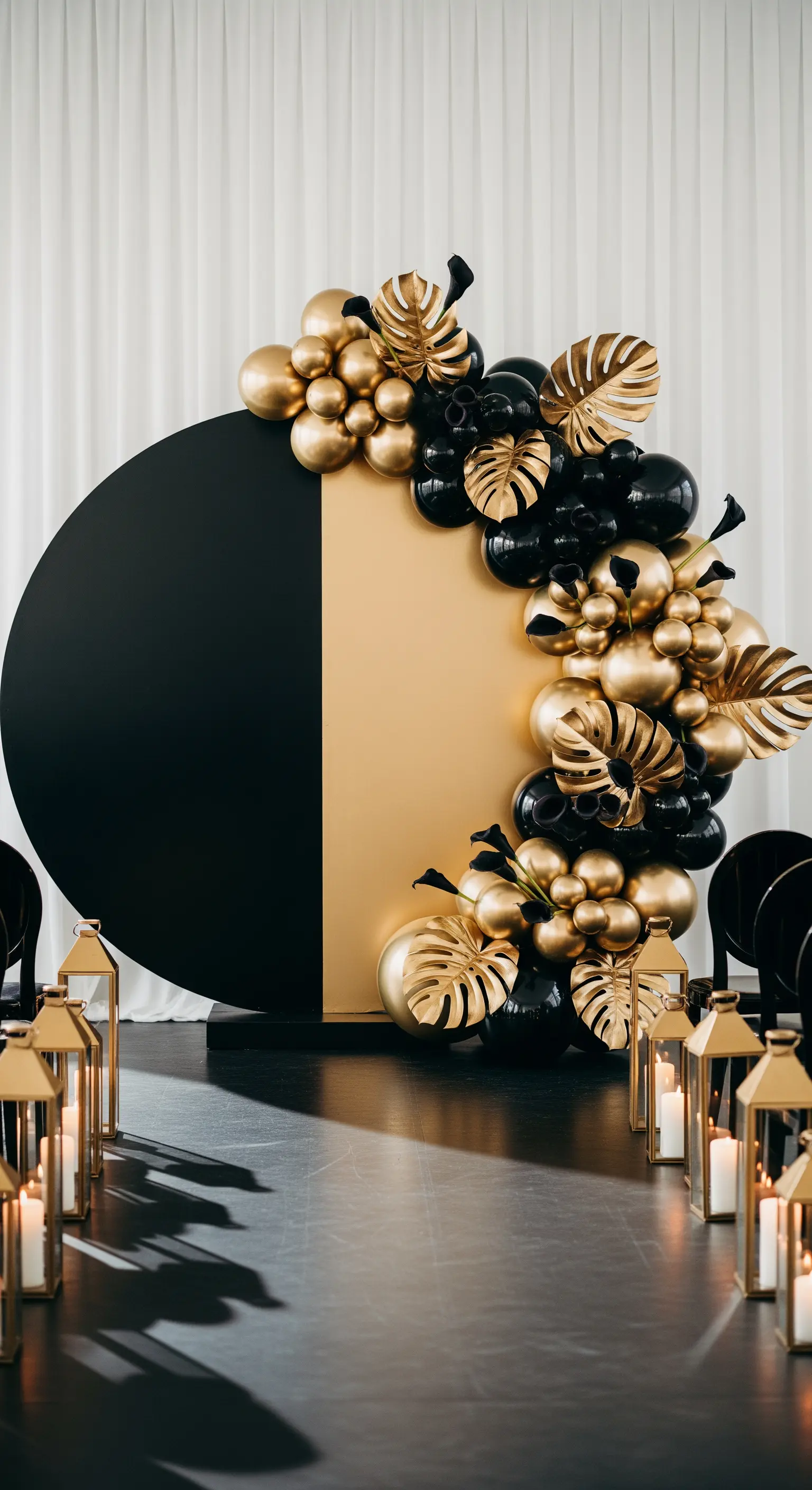 Backdrop per matrimonio bicolore, nero e oro, con palloncini e foglie di monstera dorate.