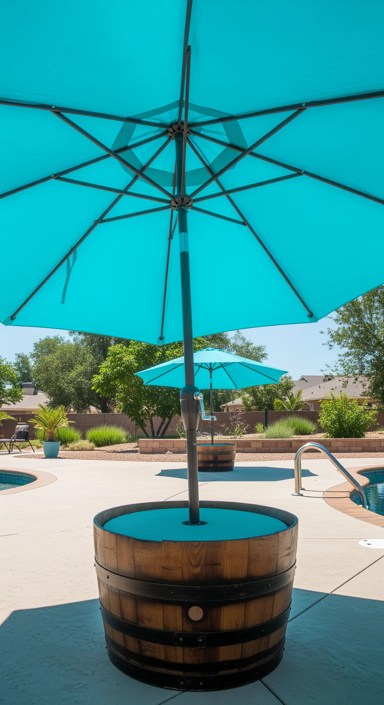 Mezza botte di vino utilizzata come base stabile per un grande ombrellone da piscina di colore turchese.