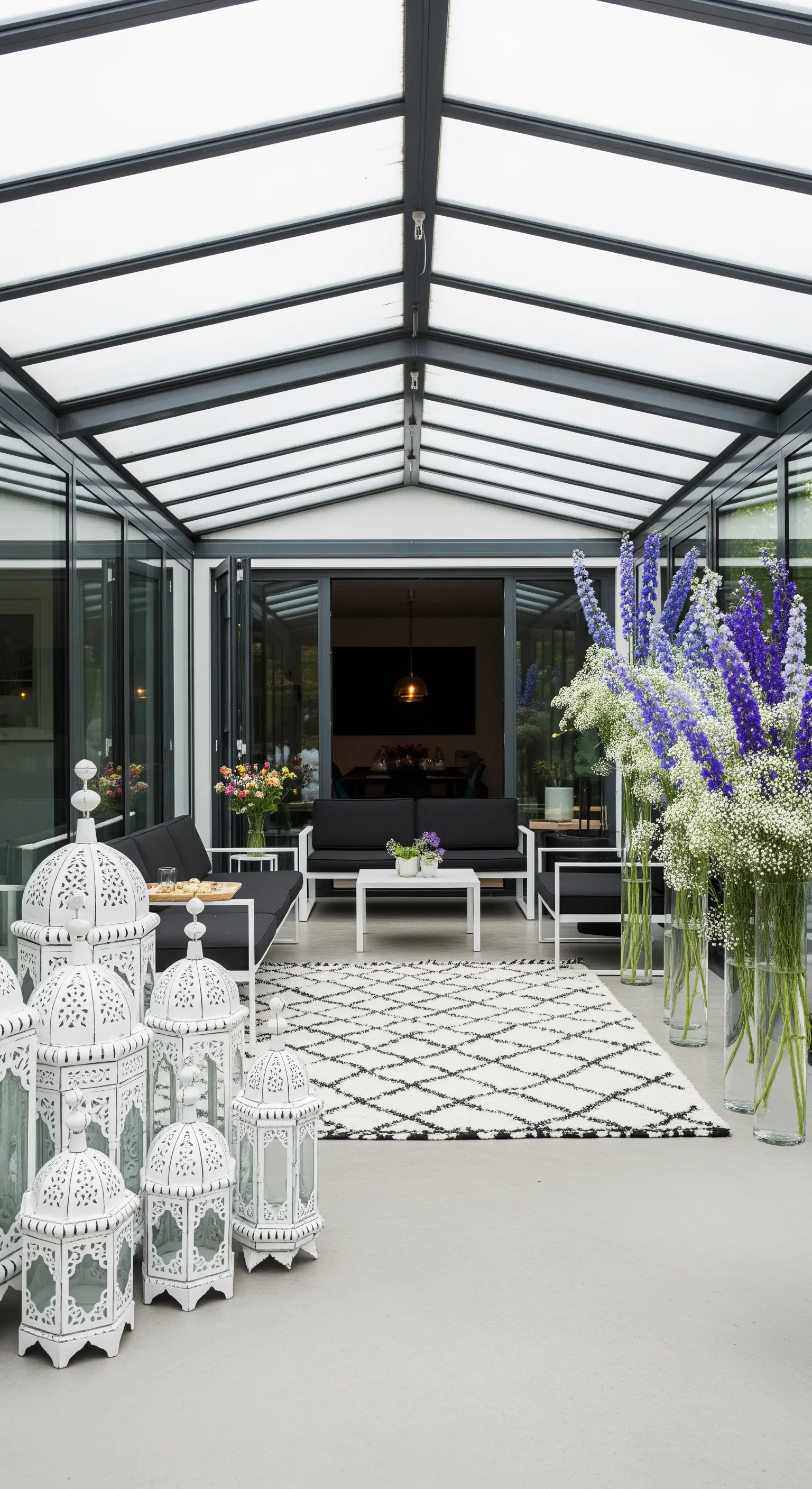 Veranda moderna con arredi neri, tappeto berbero e grandi lanterne bianche.