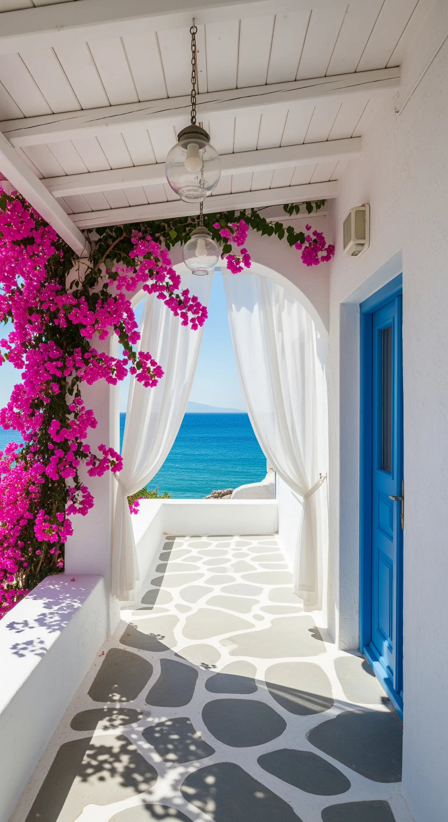 Balcone bianco in stile greco con bouganville fucsia, tende bianche e vista sul mare.