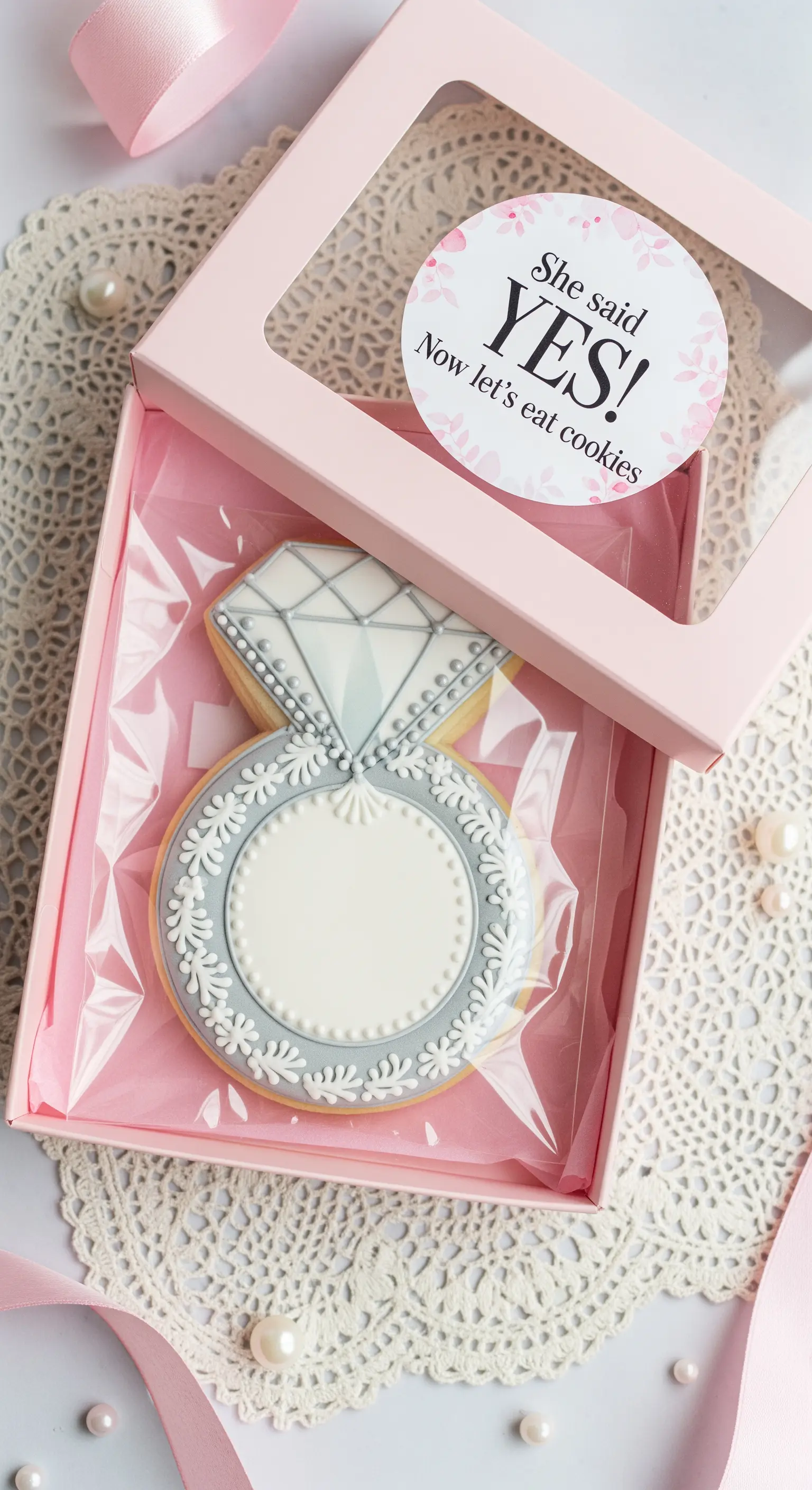 Biscotto decorato a forma di anello di fidanzamento in una scatola regalo rosa.