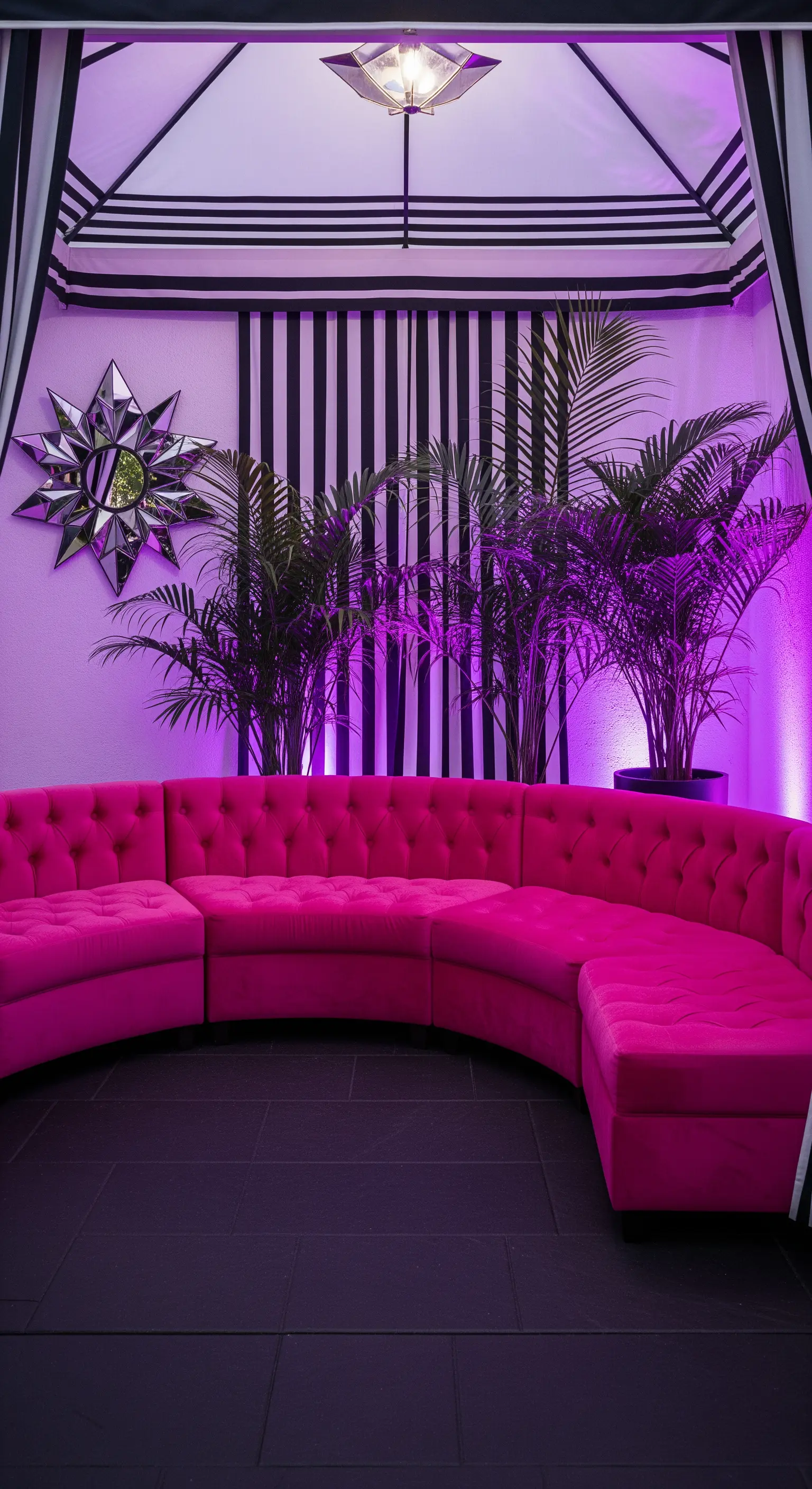 Gazebo con divano curvo fucsia, pareti a righe bianche e nere e illuminazione viola.