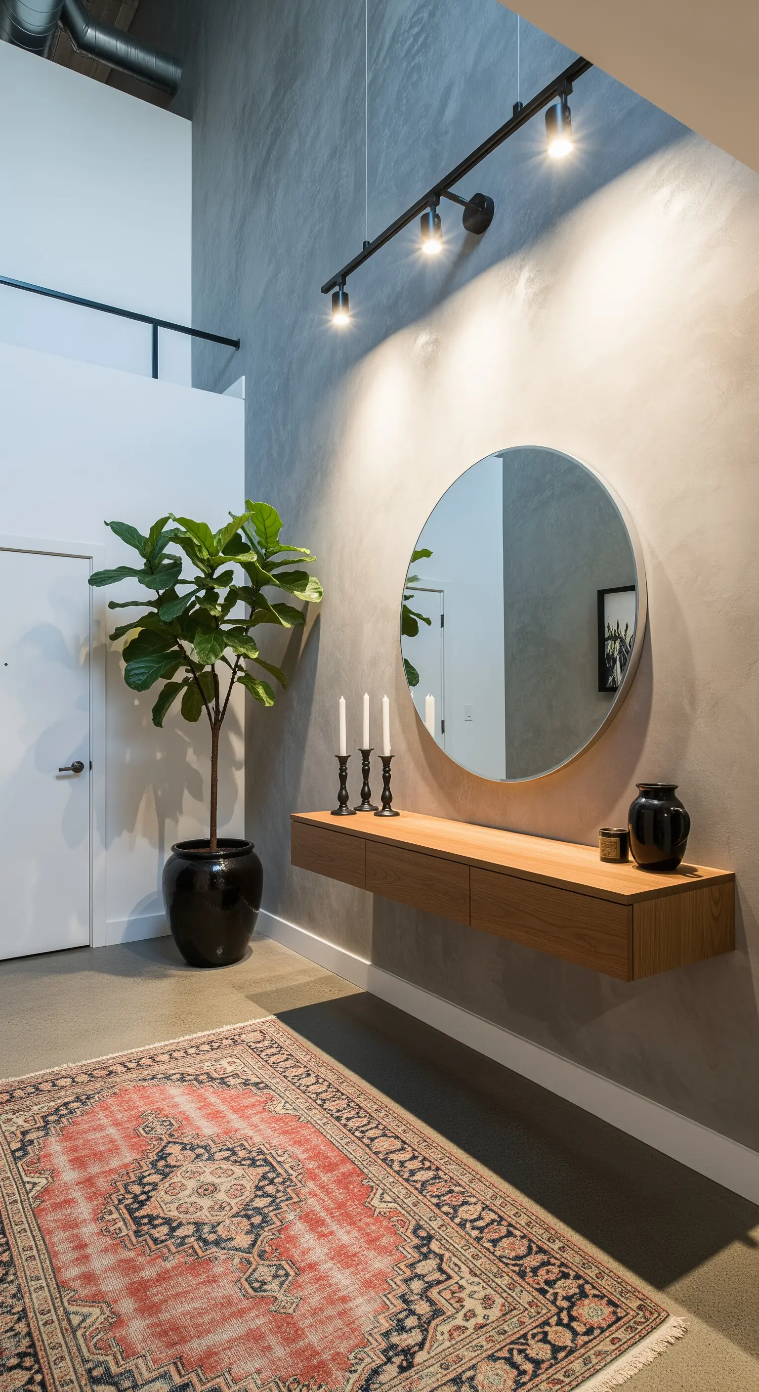 Ingresso moderno con parete effetto cemento, consolle in legno sospesa e specchio rotondo.