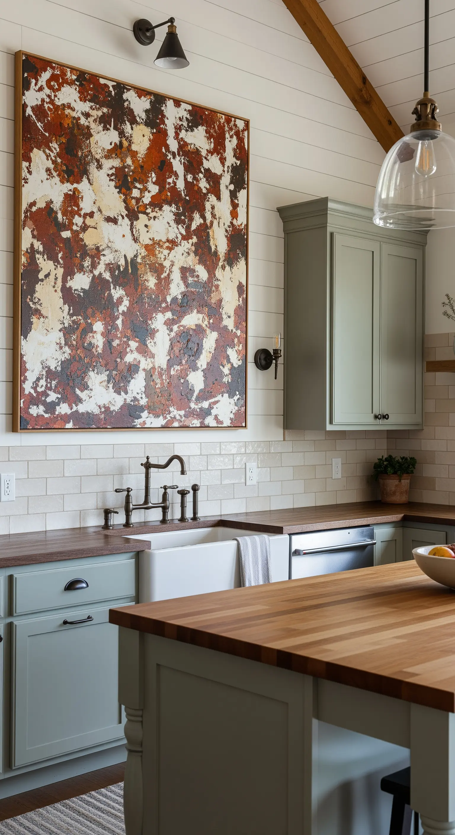 Cucina rustica con mobili color salvia, top in legno e un quadro astratto materico.