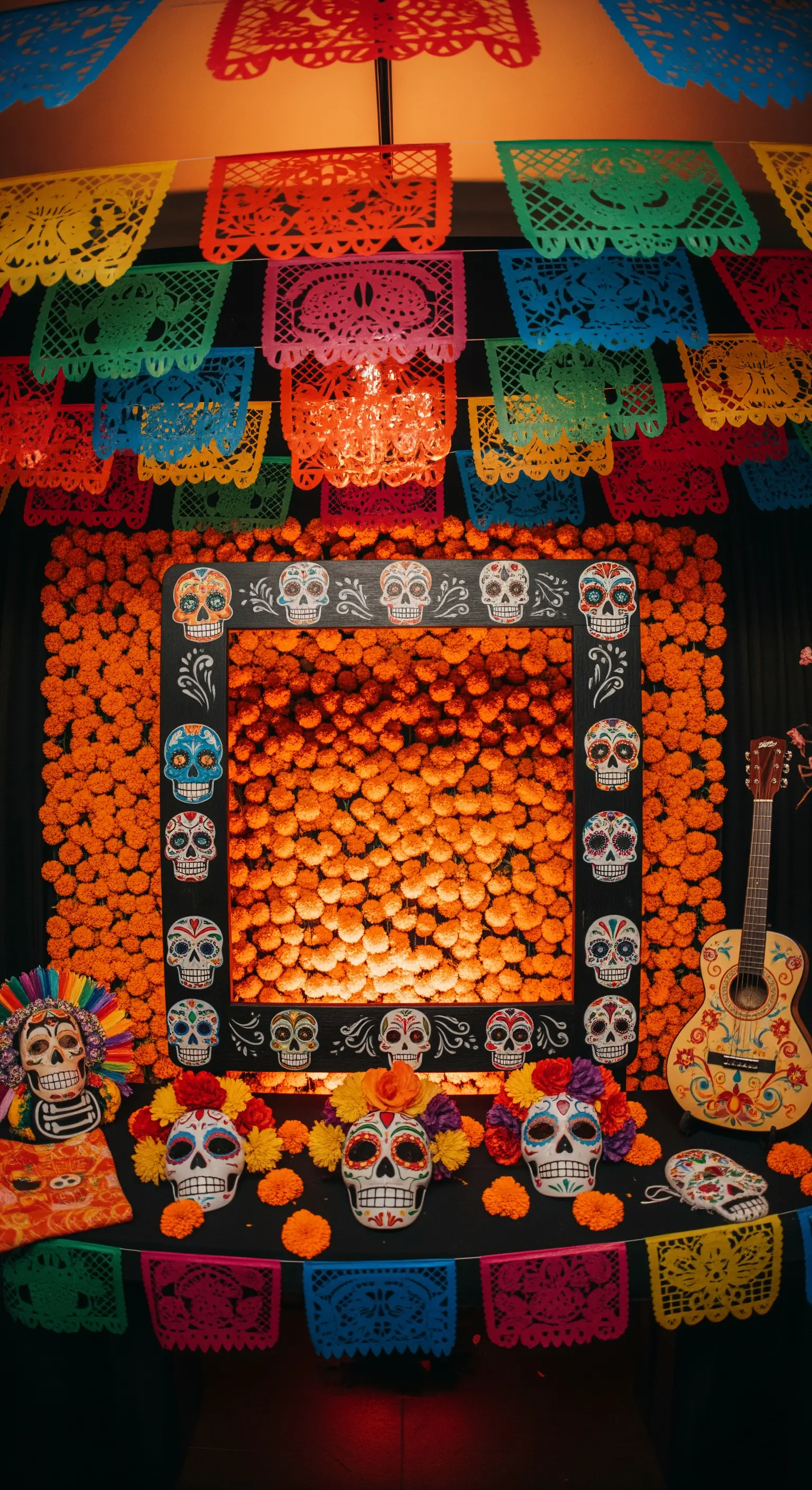 Photo booth a tema Día de los Muertos con fiori arancioni, papel picado e teschi di zucchero.