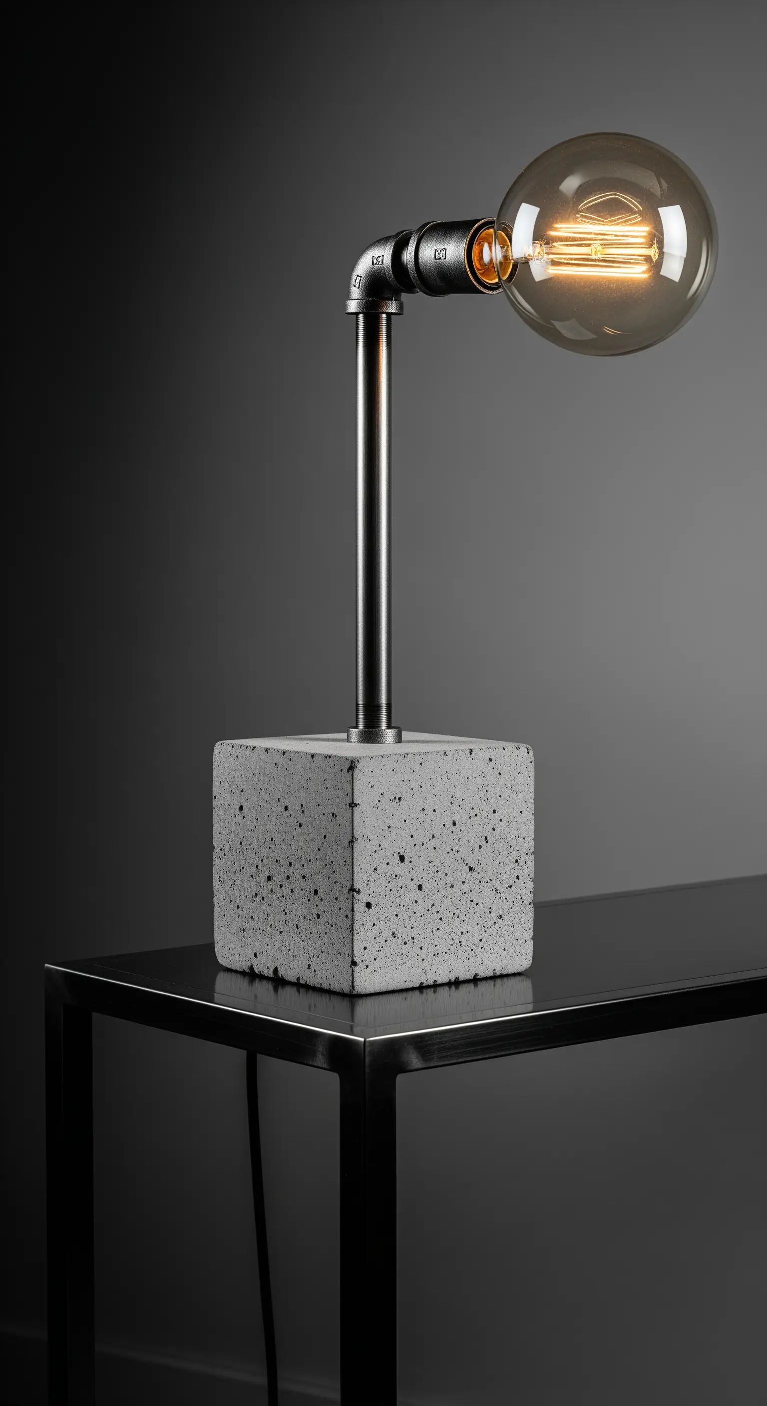 Lampada industrial con base a cubo in cemento grezzo e stelo in tubo metallico.