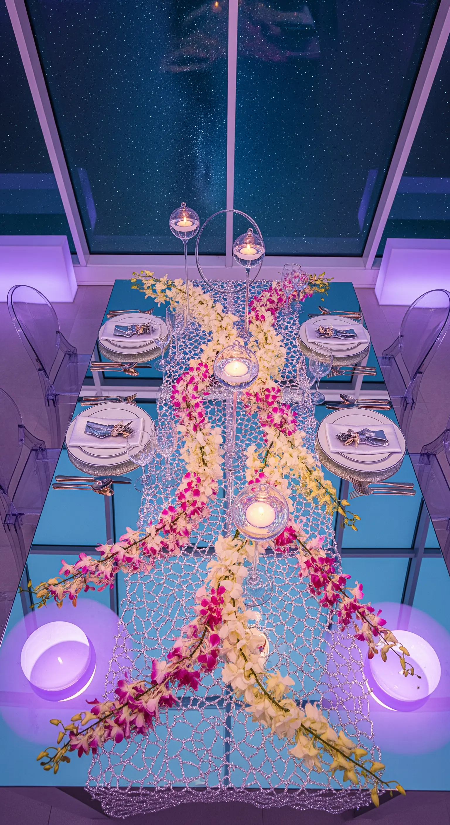 Tavolo a specchio sotto un cielo notturno, decorato con un runner di cristalli e orchidee.