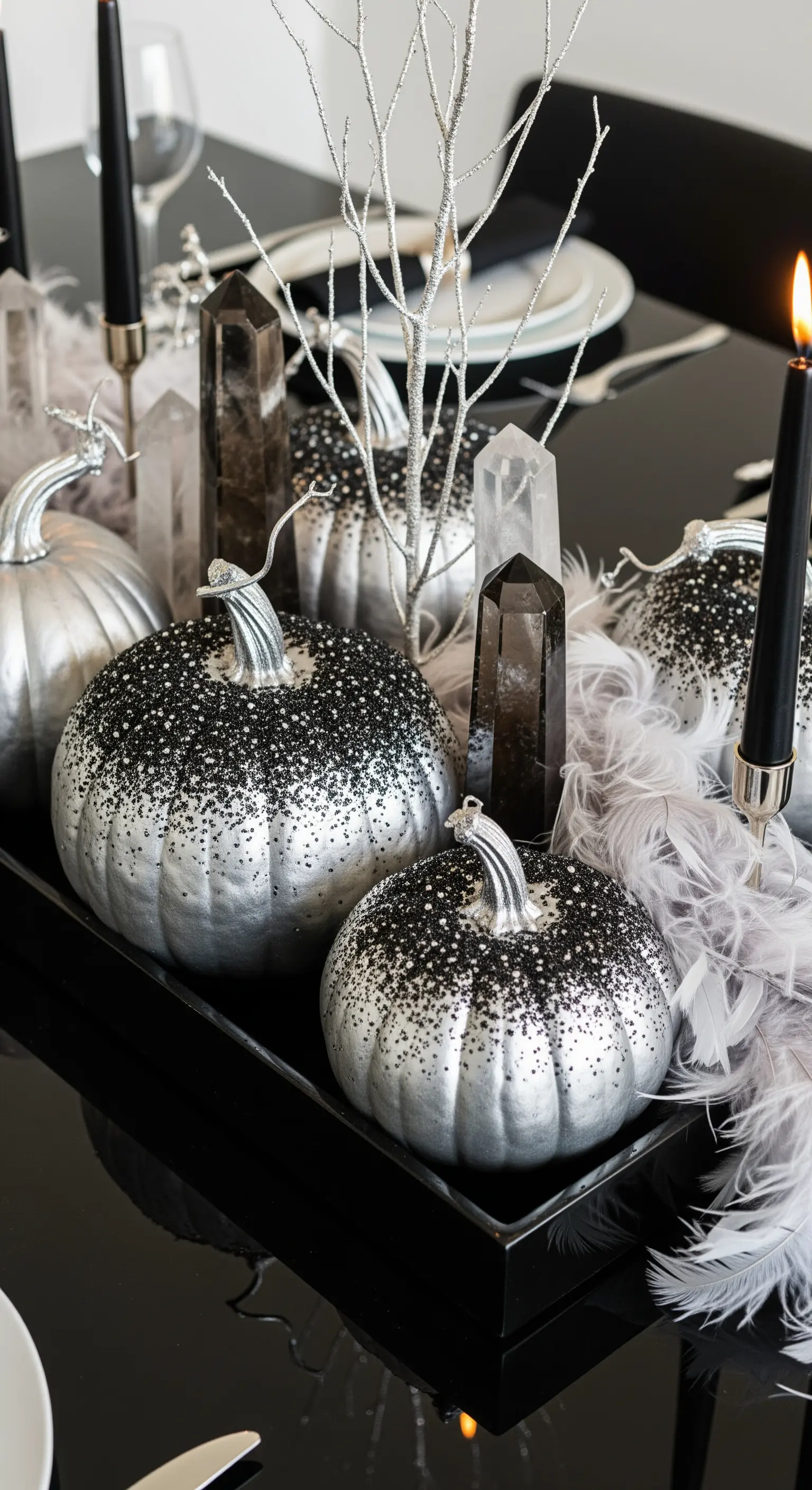 Centrotavola di Halloween con zucche argento e glitter nero, cristalli e piume grigie.