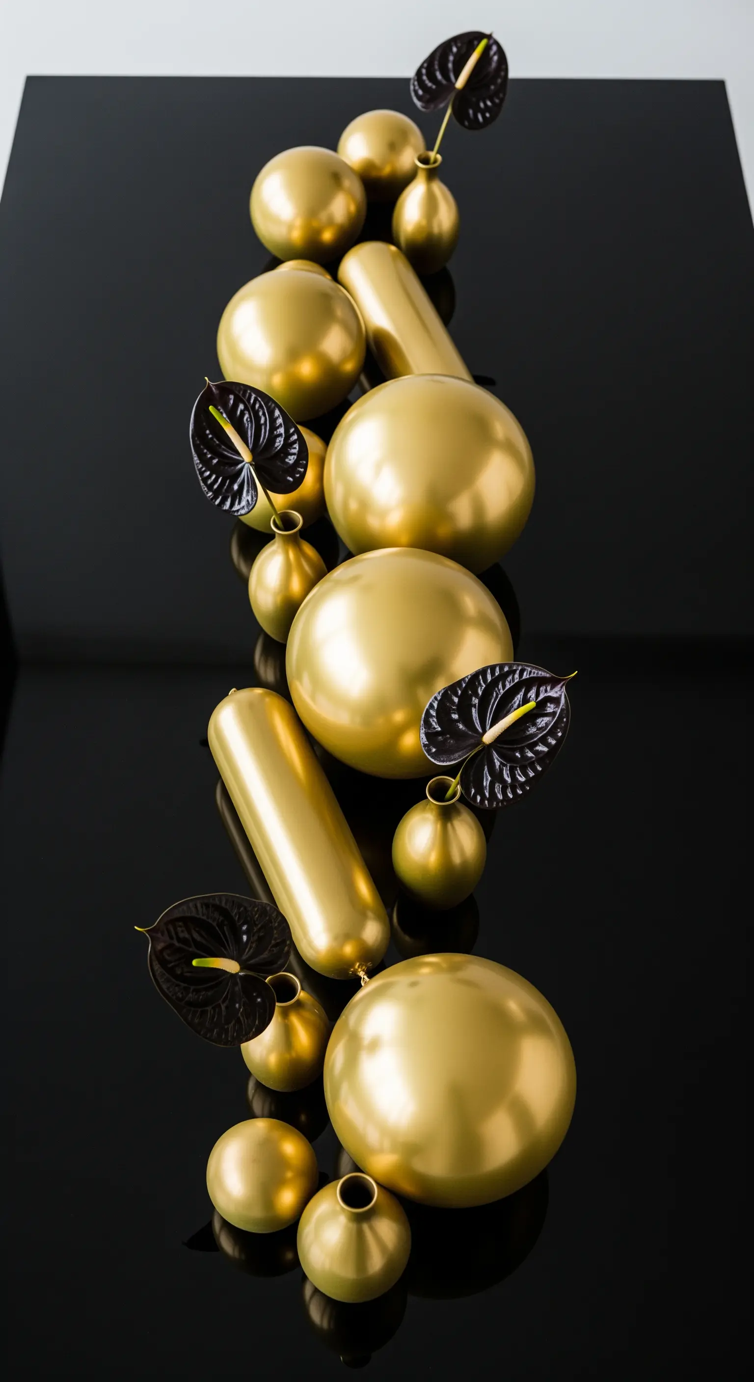 Centrotavola minimalista con palloncini dorati di varie forme e anthurium neri.
