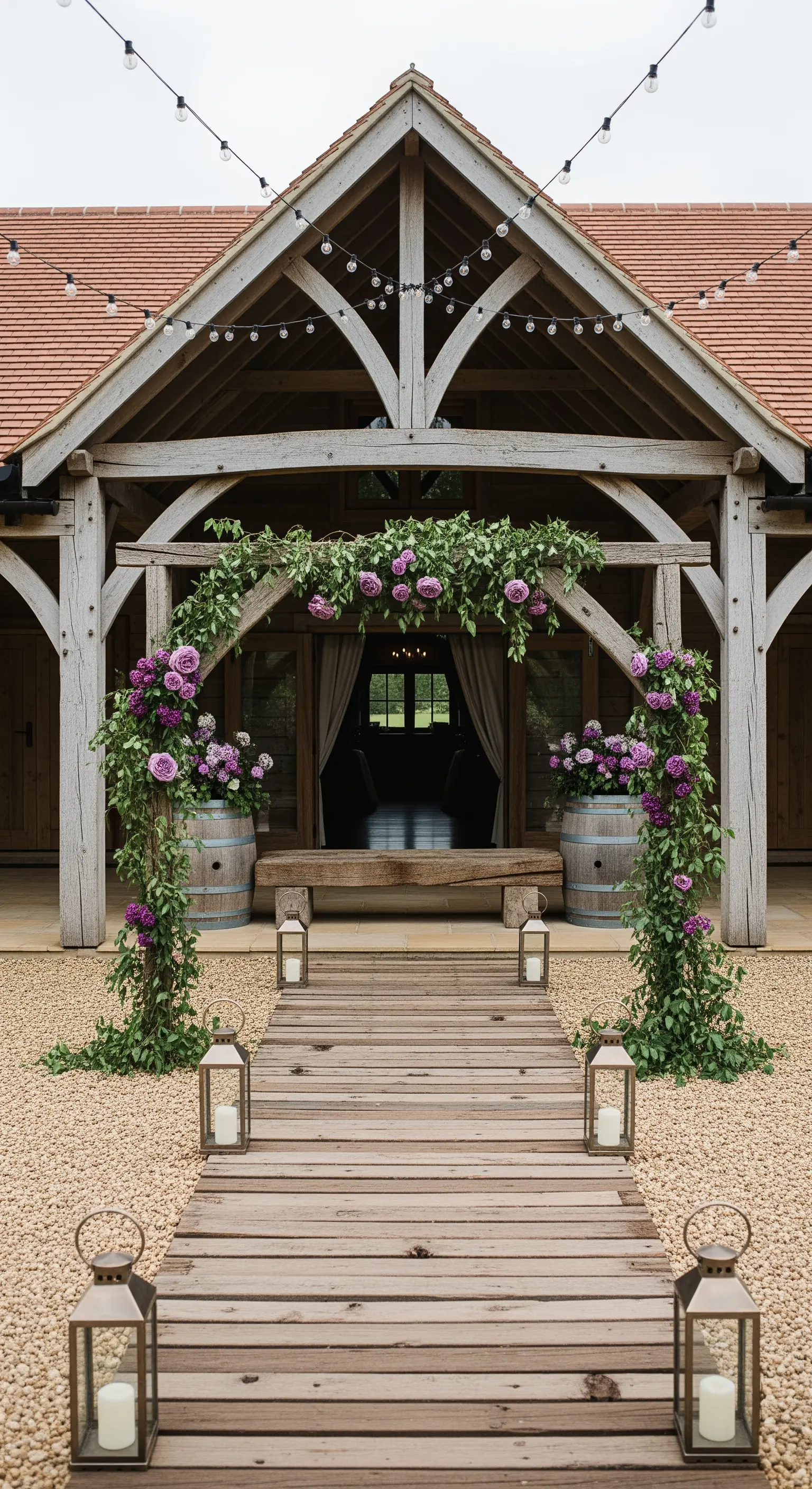 Ingresso di un fienile rustico con arco di rose viola e botti di legno come fioriere.