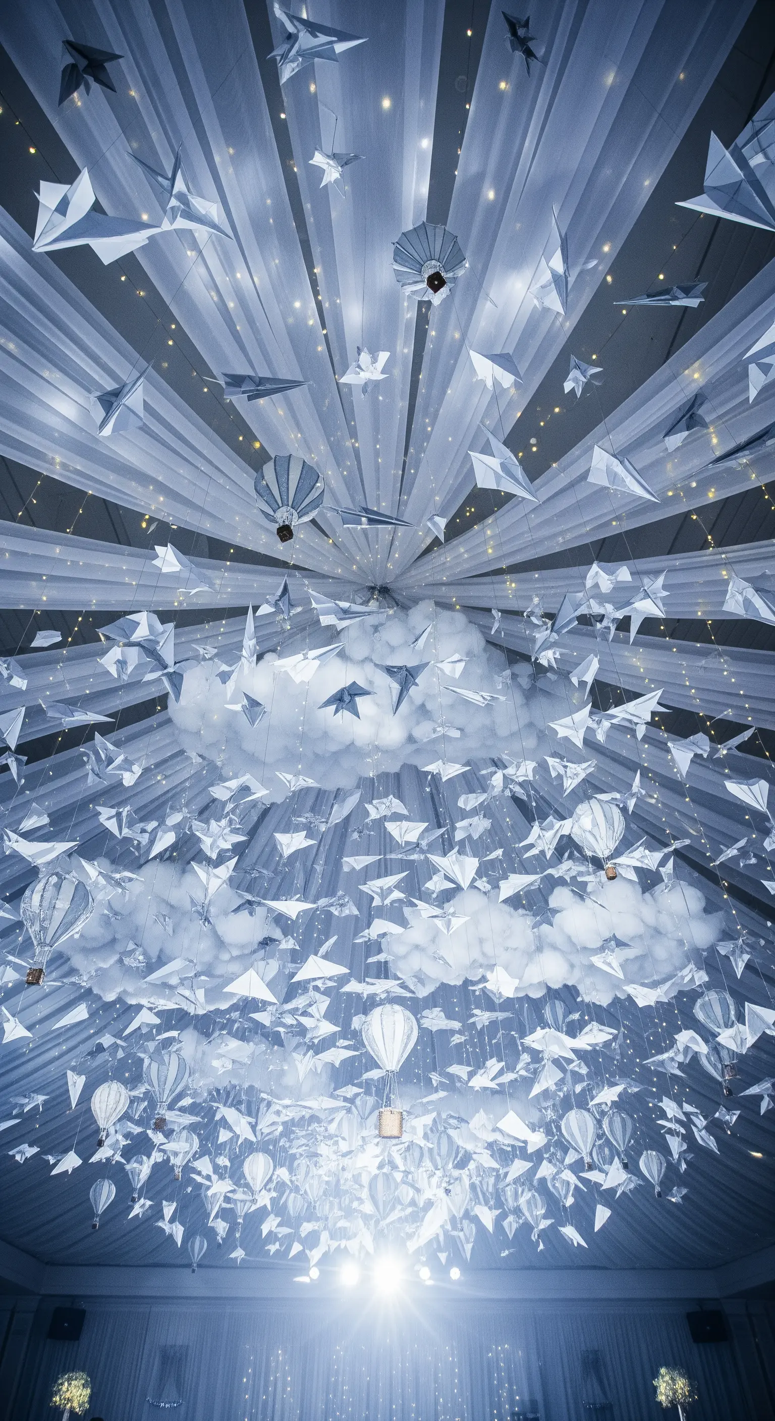 Soffitto decorato con drappi bianchi, aeroplani di carta e lucine per un effetto cielo stellato.