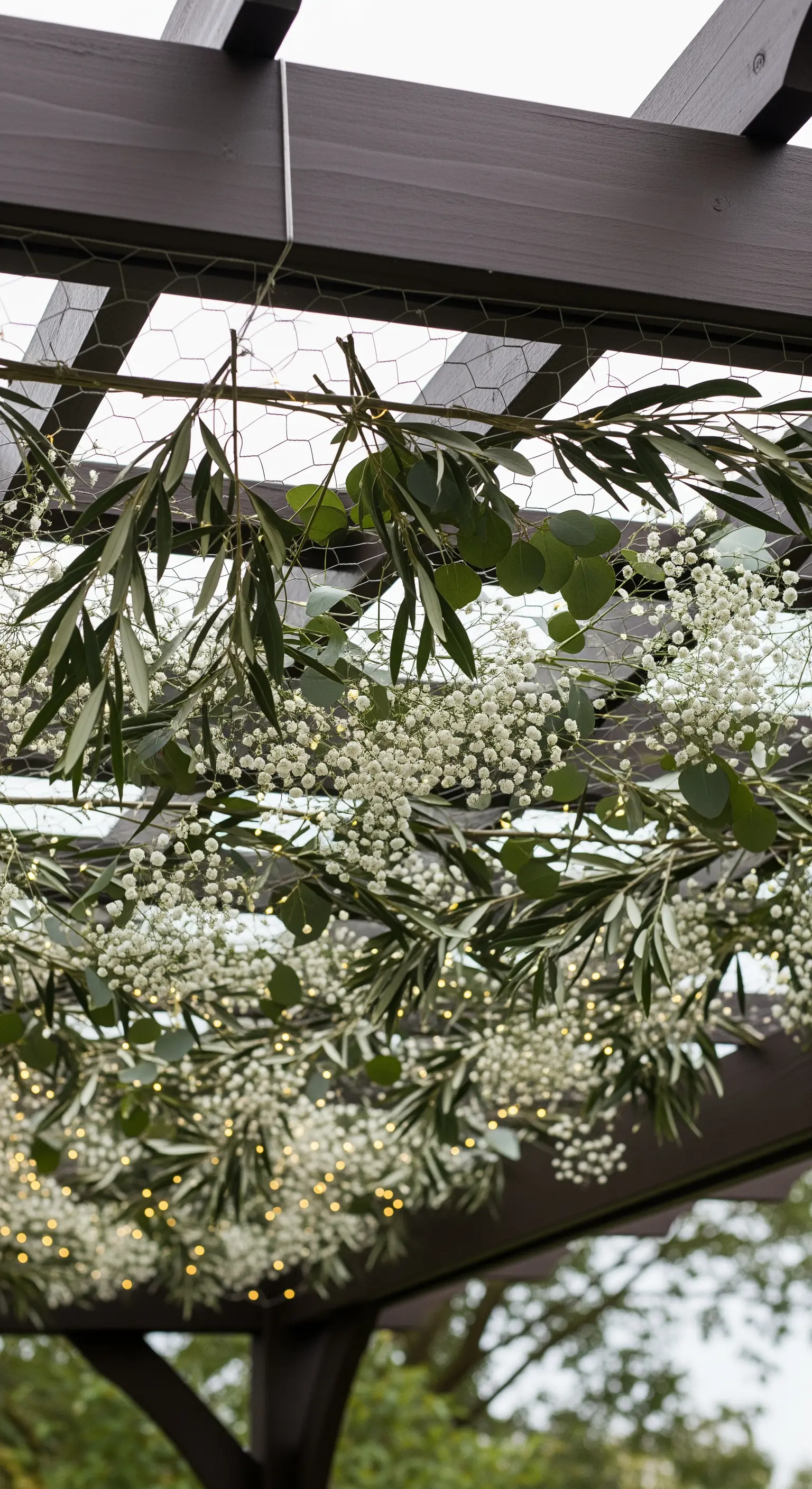 Soffitto di un pergolato decorato con fiori di gipsofila e foglie di ulivo.