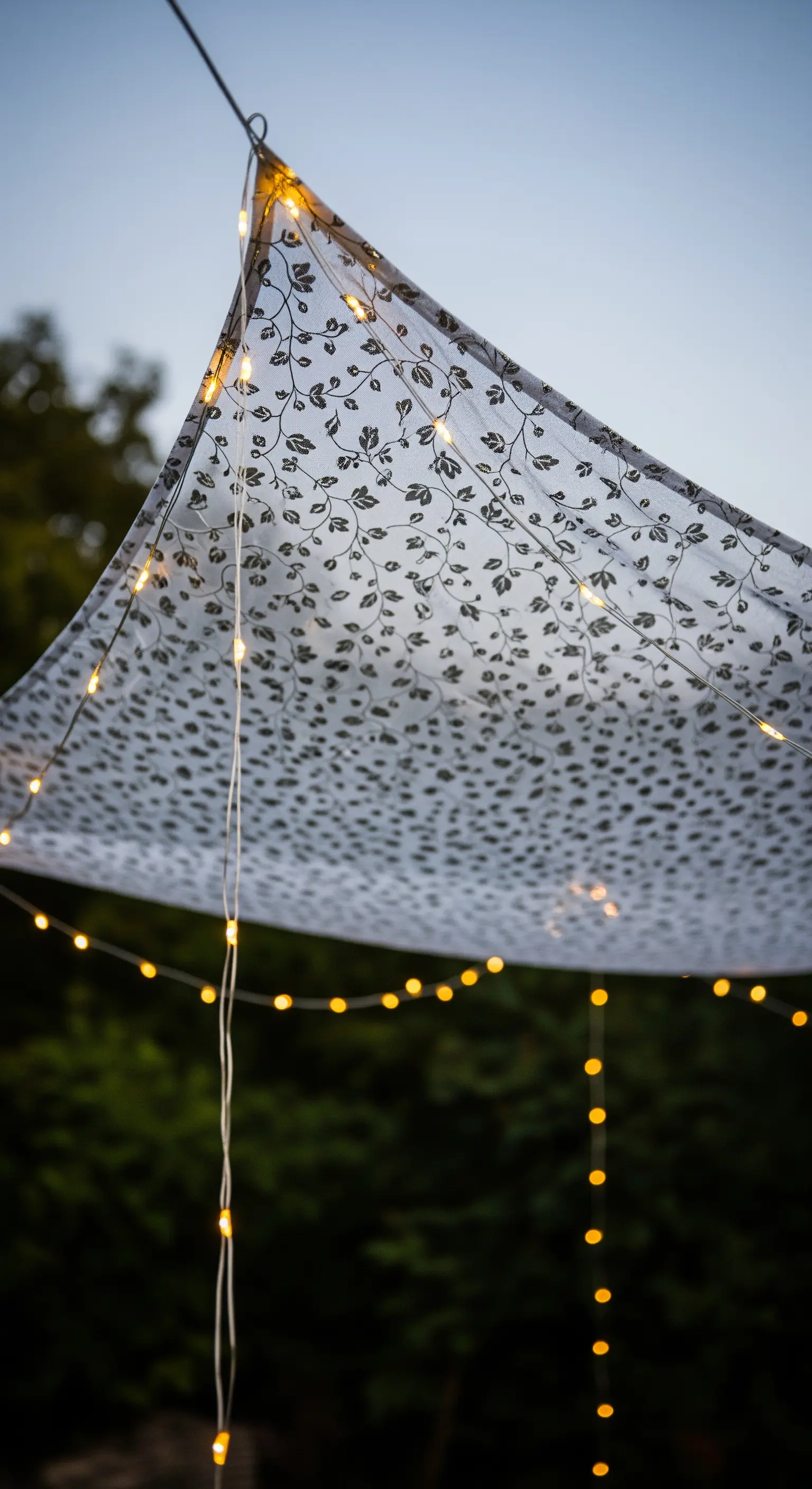 Tenda leggera con stampa floreale e fili di lucine calde per un'atmosfera serale.
