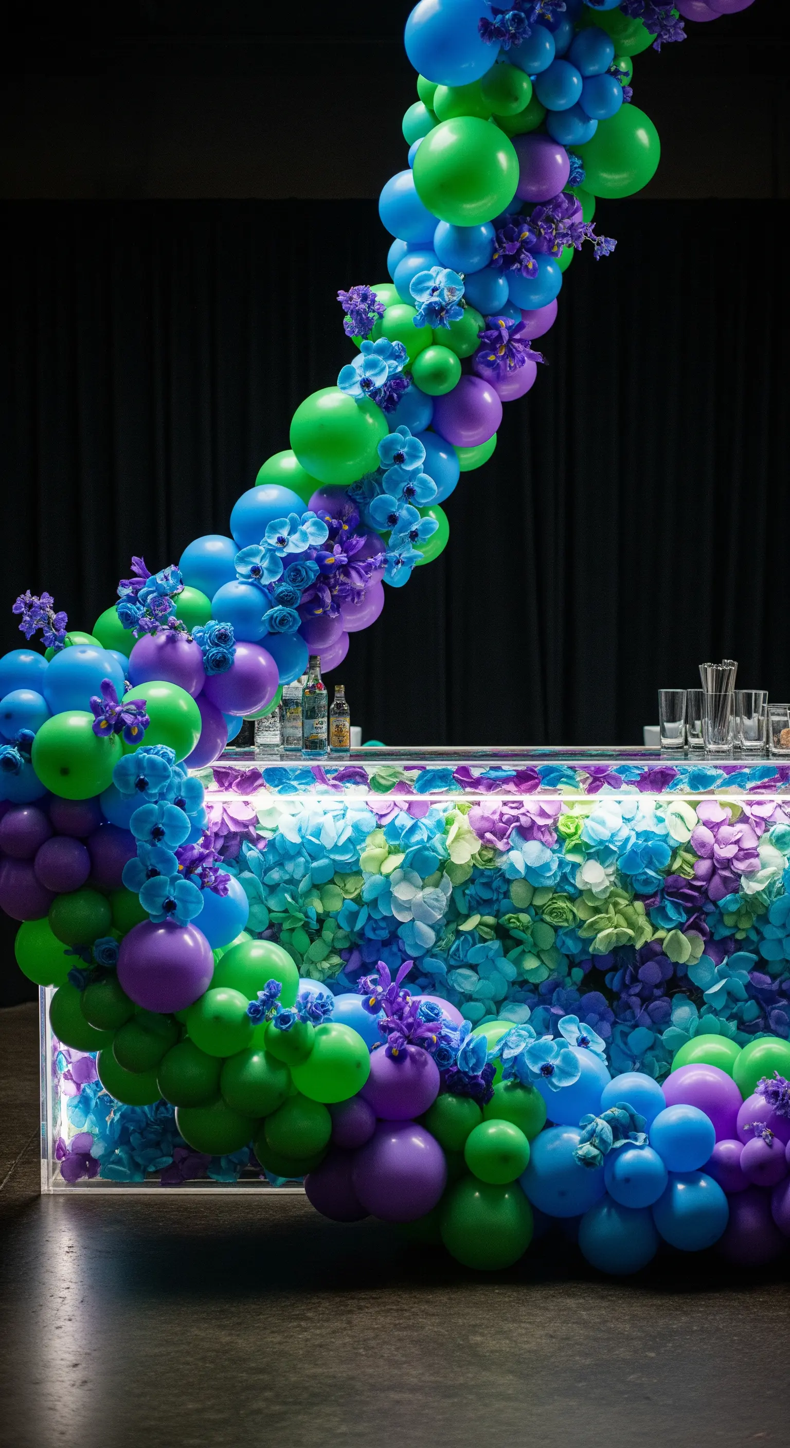 Bancone bar rivestito di fiori blu e viola, incorniciato da palloncini coordinati.