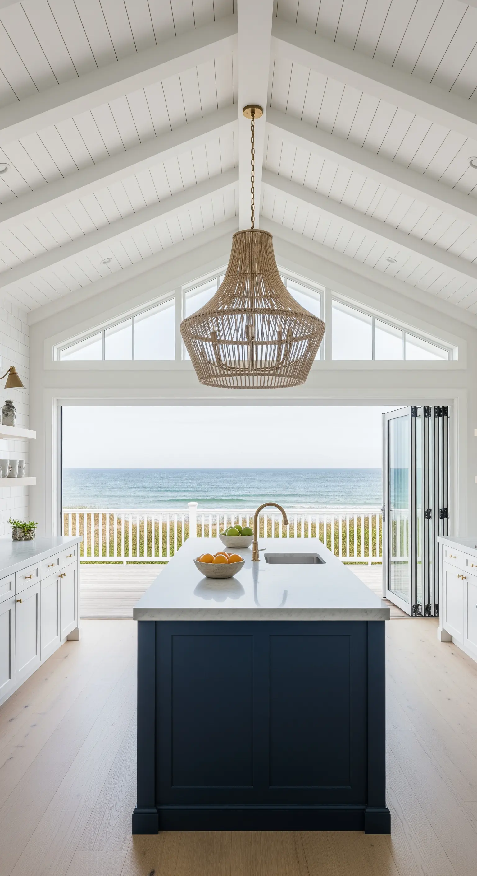 Cucina bianca e blu con soffitto a capanna, lampadario in rattan e vista sull'oceano
