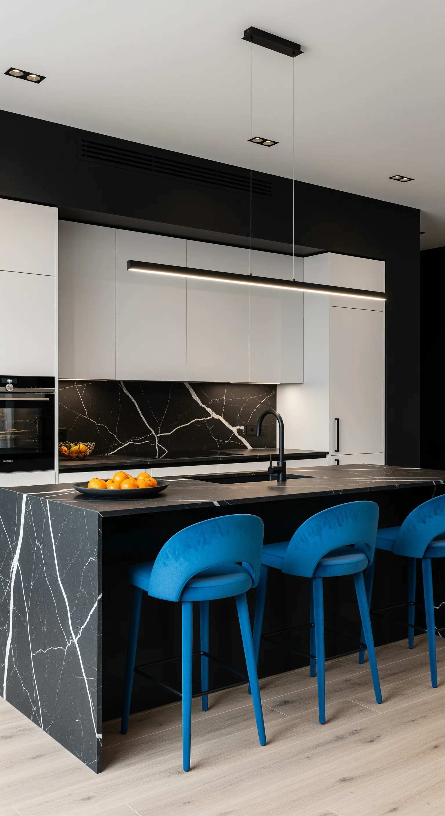 Cucina in bianco e nero con penisola in marmo nero venato e sgabelli in velluto blu elettrico
