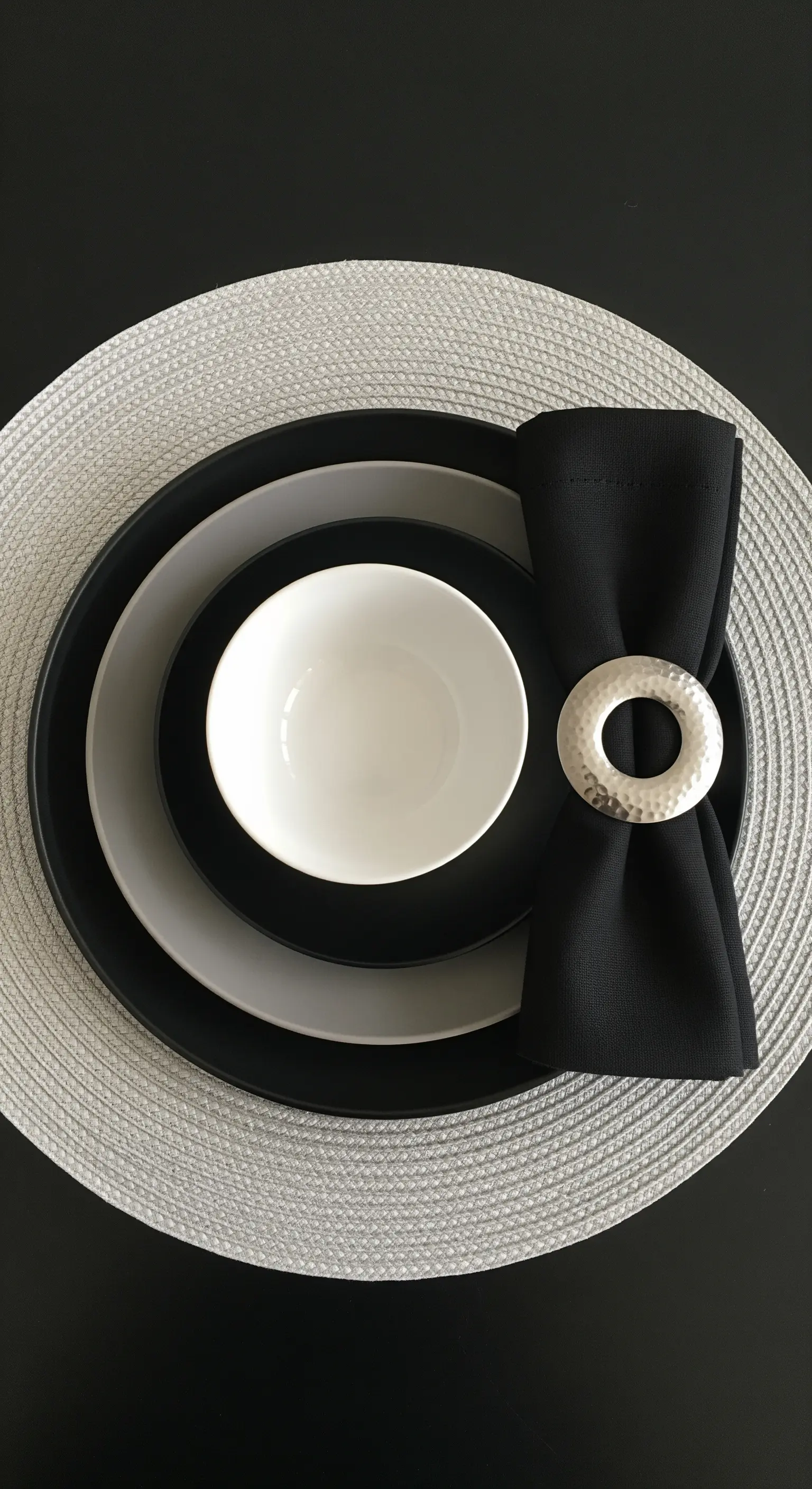 Dettaglio di un'apparecchiatura in bianco, nero e grigio con portatovagliolo martellato.