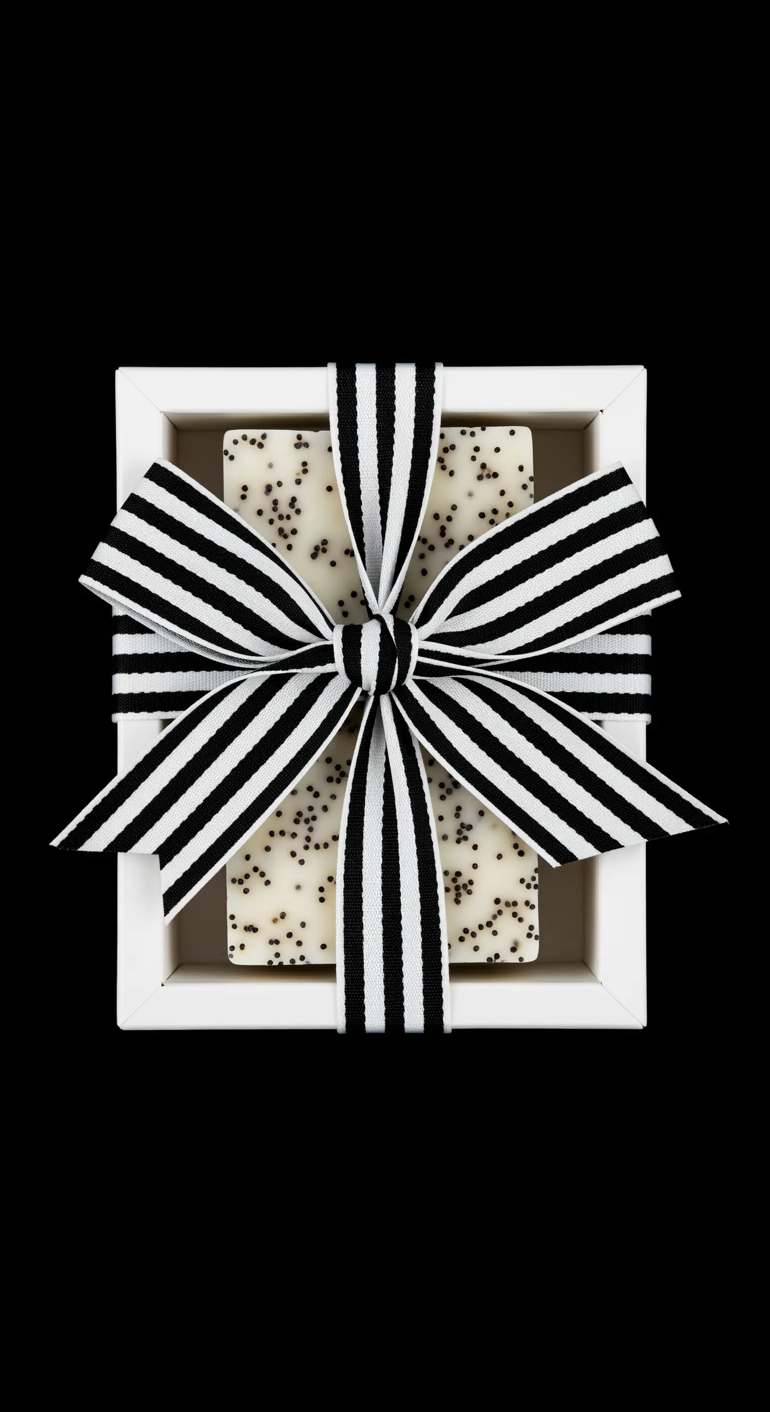 Sapone bianco con semi di papavero in una scatola bianca, con un fiocco a righe bianche e nere.